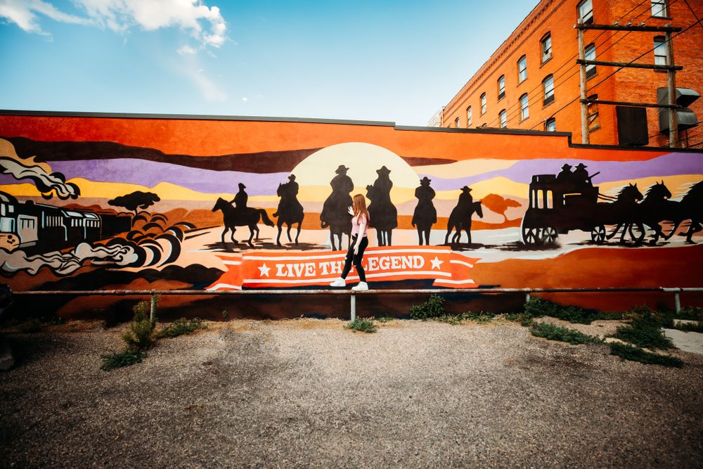Senior girl walking next to mural in downtown Cheyenne, WY
