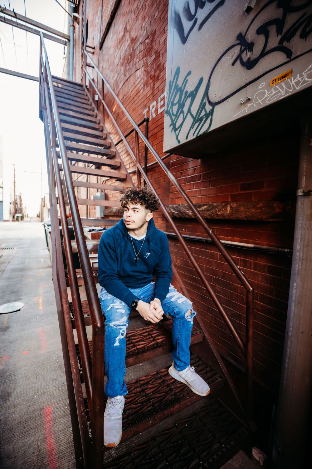Senior boy poses on alleyway stairs in Dickson, TN