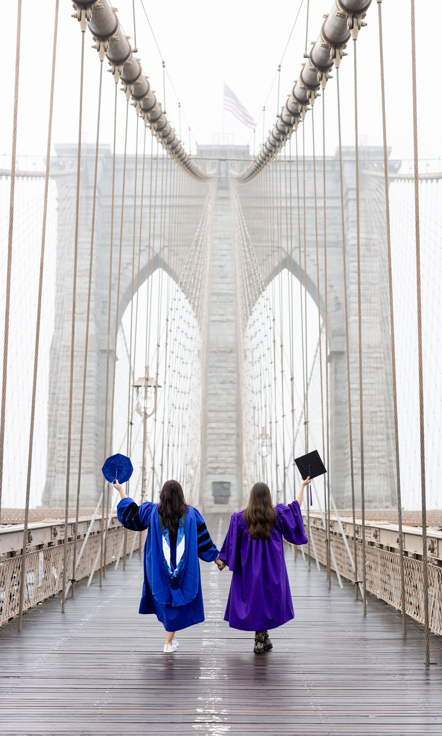 Group wearing purple graduation gowns sitting by fountain in celebratory pose.