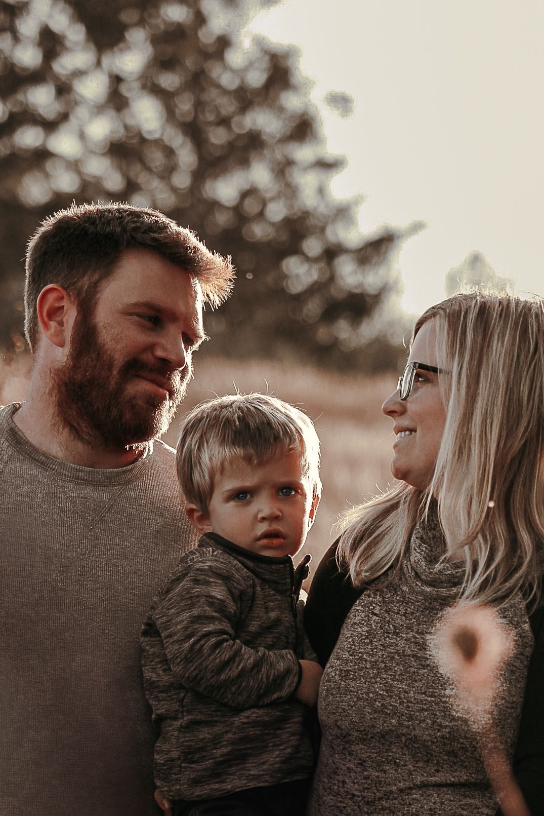 Intimate family portrait captured during golden hour with soft bokeh background.