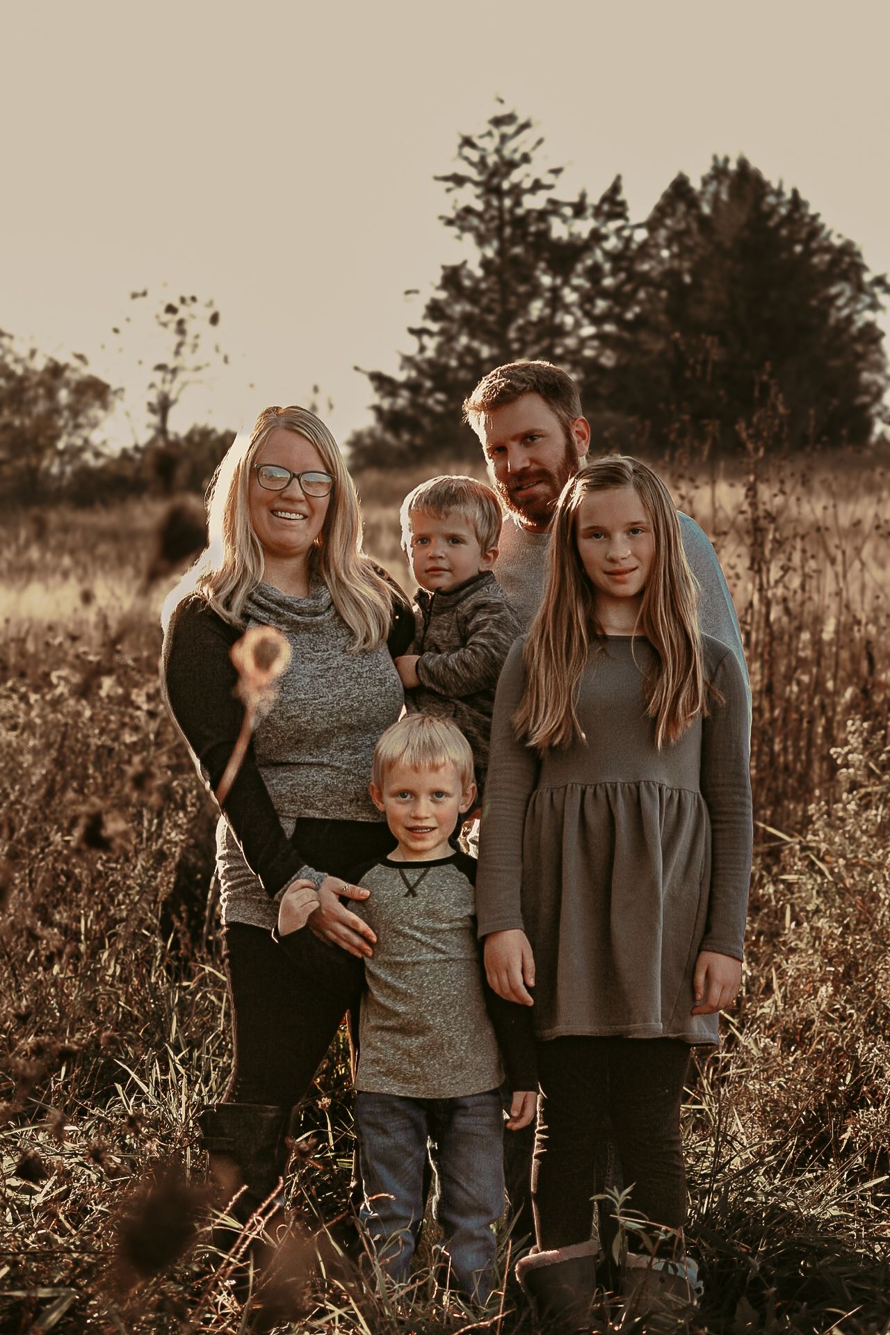 Family of five poses together in autumn field during golden hour.