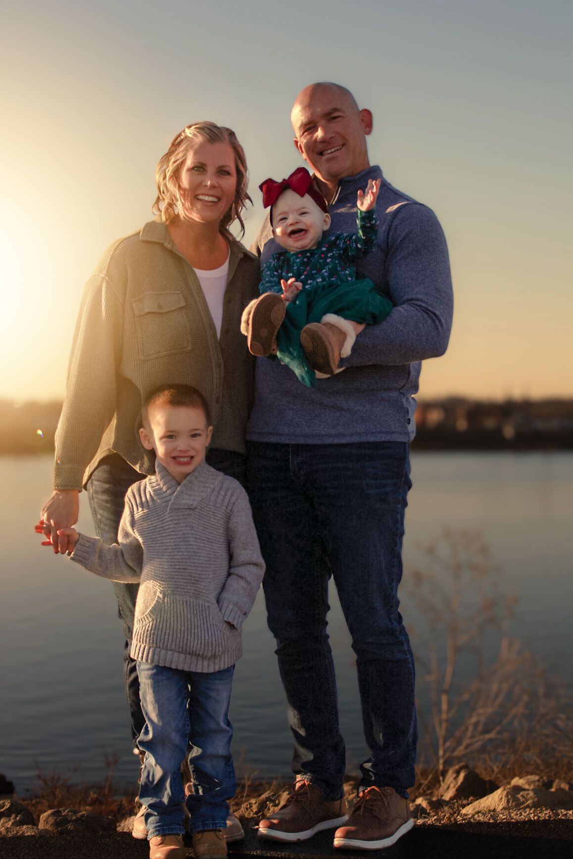 Family portrait at sunset by waterfront with warm golden lighting.
