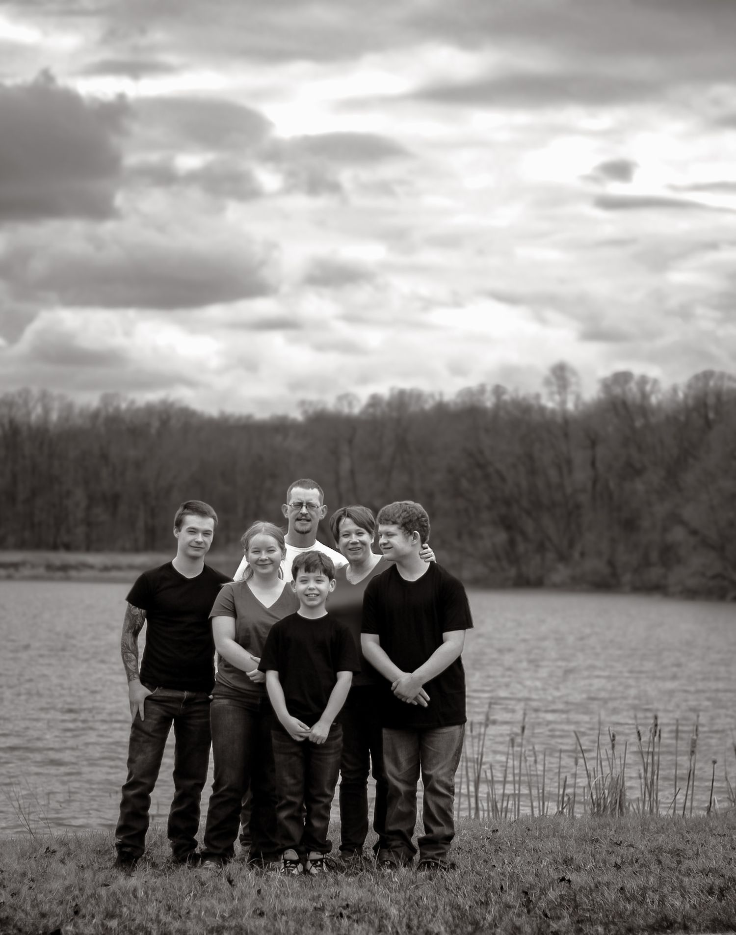 Black and white landscape photo of people gathered near a lake with reeds.