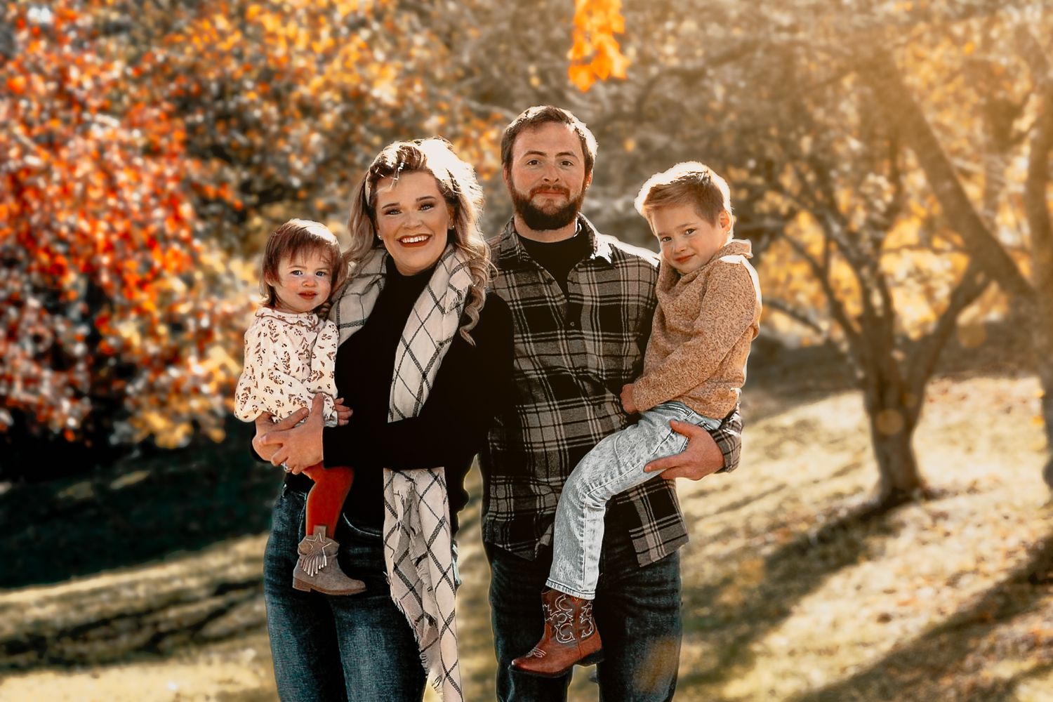 Joyful outdoor family photography session with golden sunlight filtering through autumn trees.