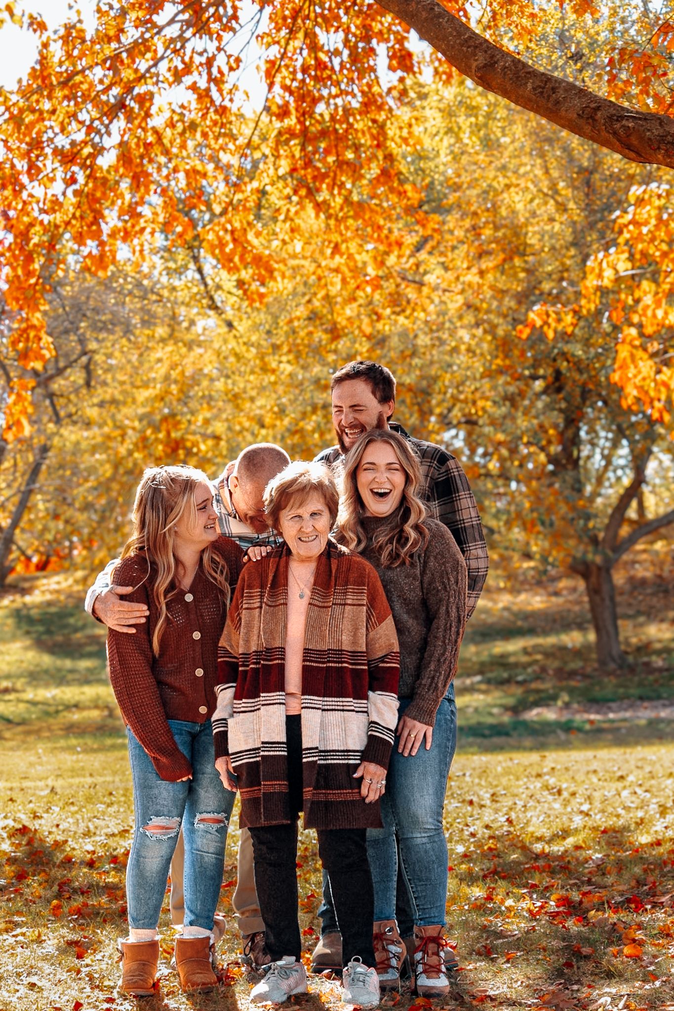 Laughter-filled family photo session under vibrant orange fall foliage.