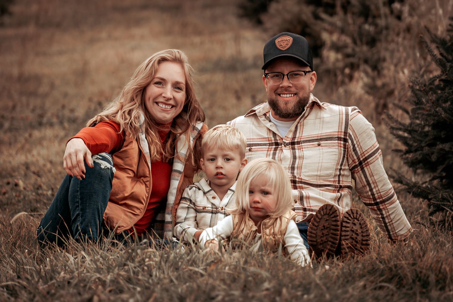 Cozy fall family portrait in rustic outdoor setting with warm autumn colors.