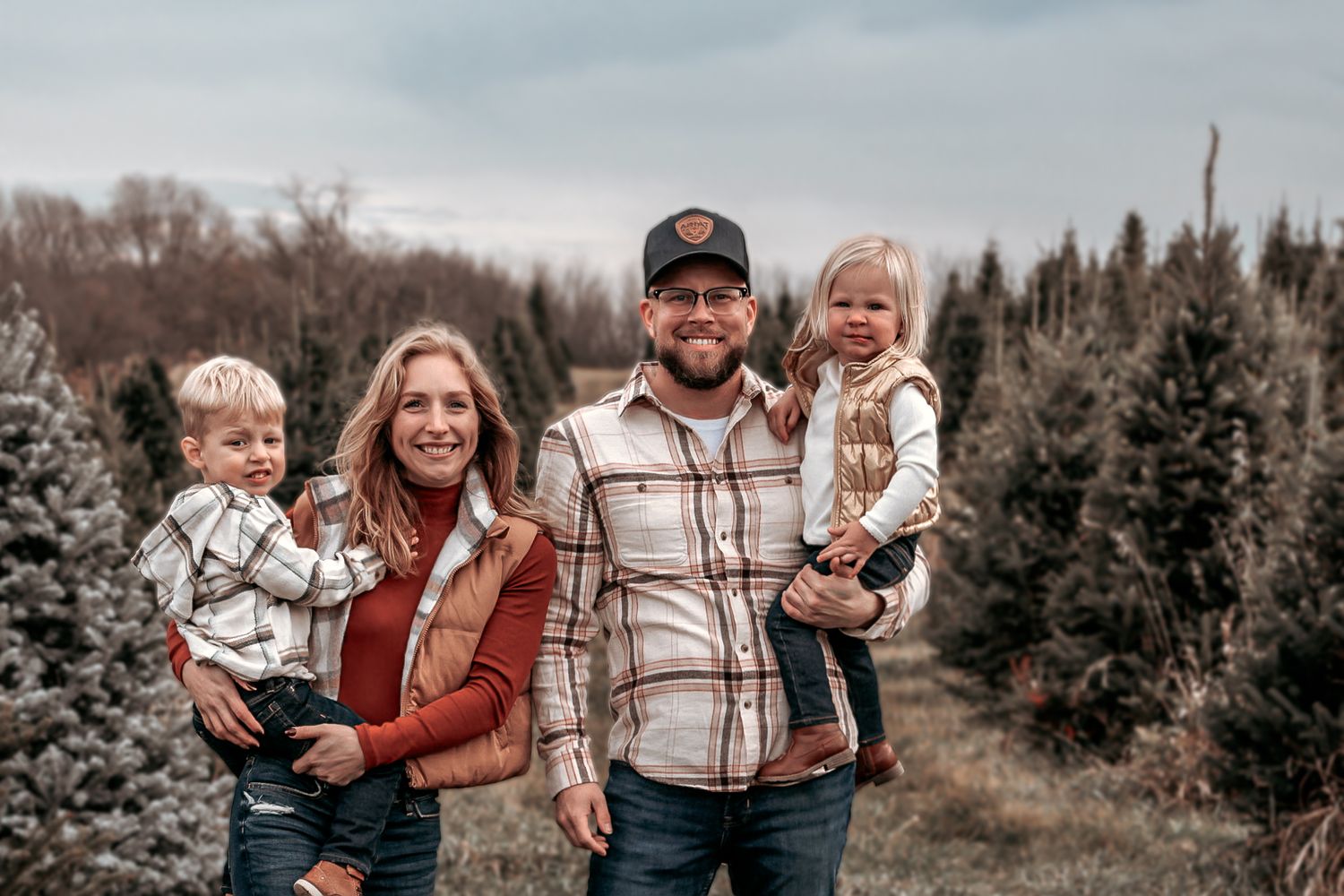 Lifestyle family portraits taken at a Christmas tree farm on a cloudy winter afternoon.