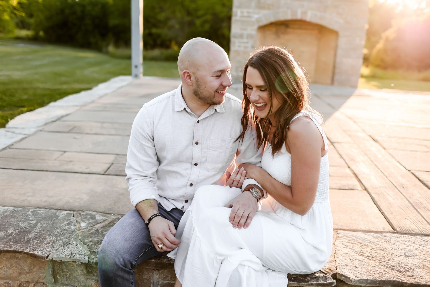 Romantic outdoor wedding photoshoot at sunset with couple sitting on wooden deck.