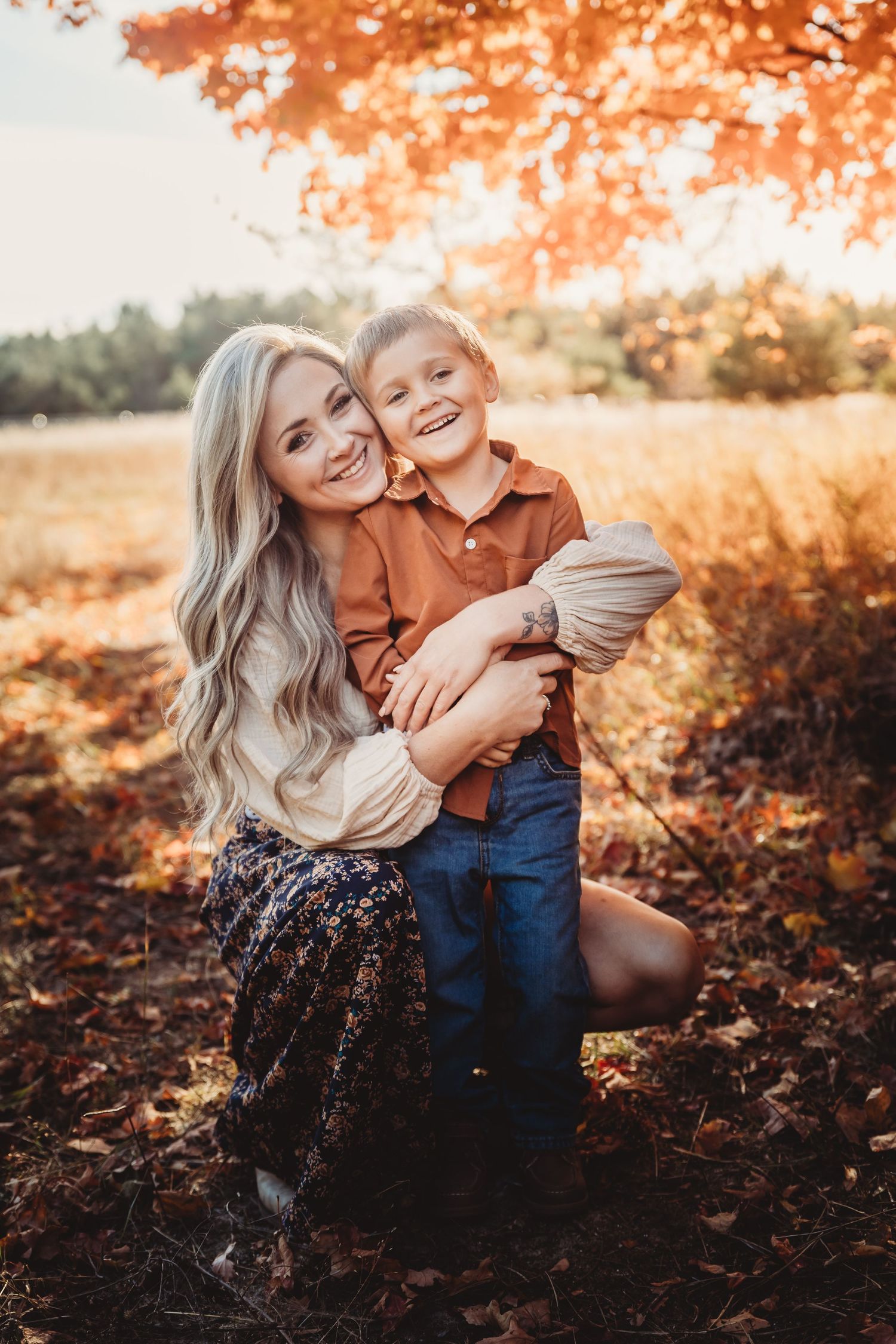 Autumn family photoshoot with golden sunlight filtering through orange leaves in a park setting.