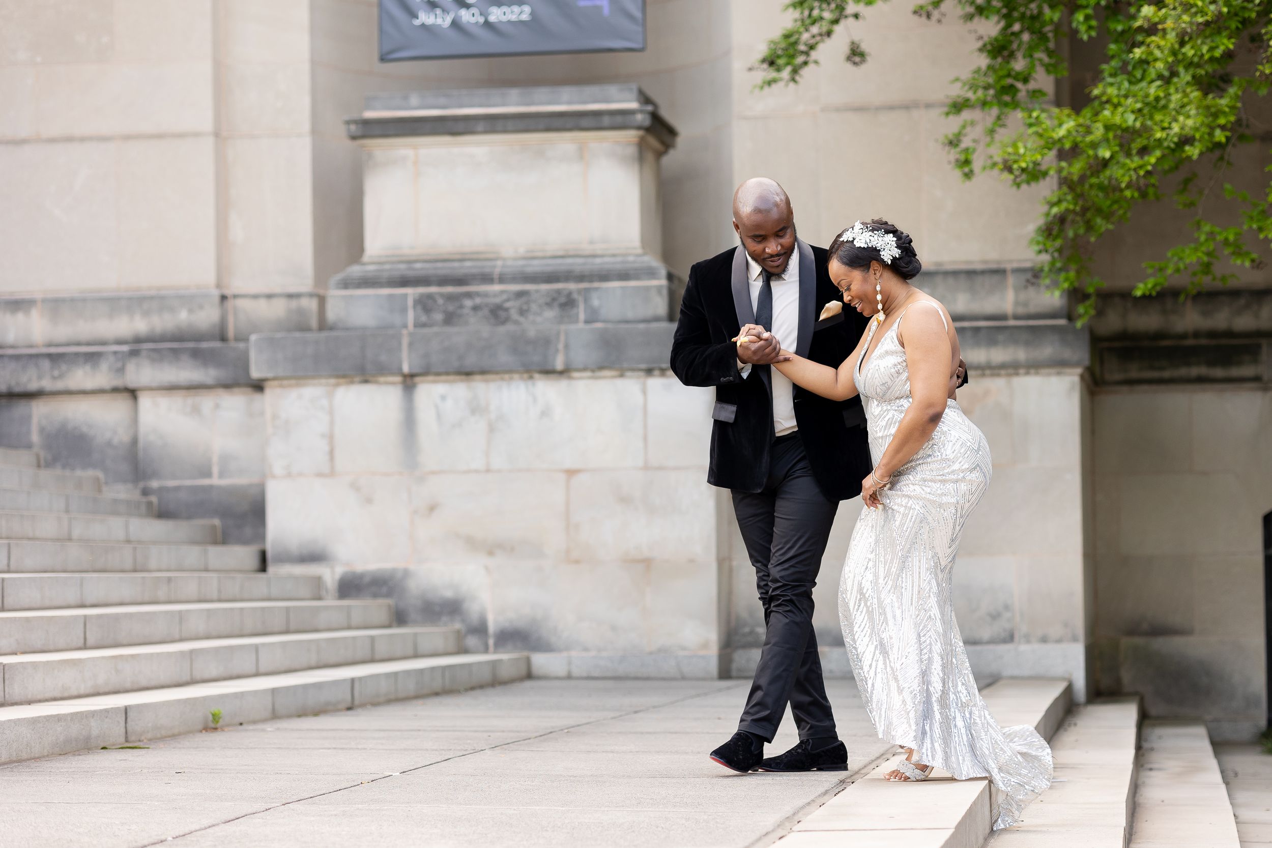 Bride and groom walking together outside stone steps on their wedding day.