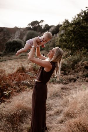 A joyful outdoor photoshoot in a grassy field shows tender moments between loved ones.