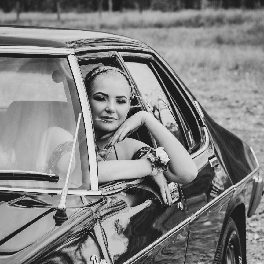 Black and white portrait of someone in a flowing tulle gown in a field.