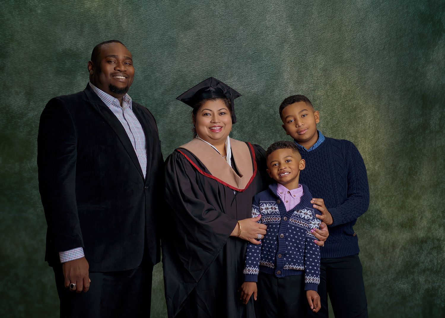 A multi-generational family group poses together in a professional studio portrait against a brown backdrop.