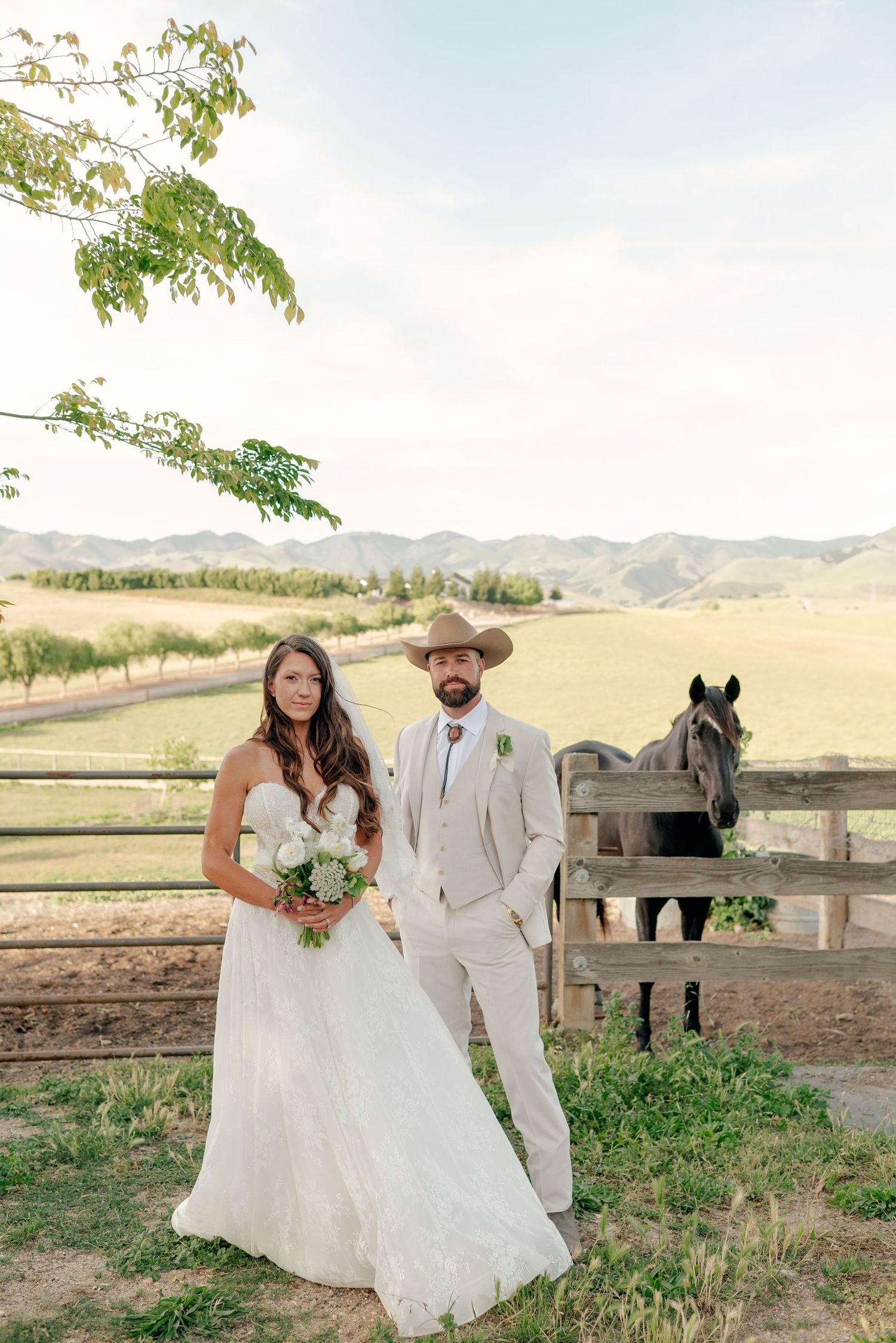 Wedding couple embracing in rustic outdoor setting during sunset.
