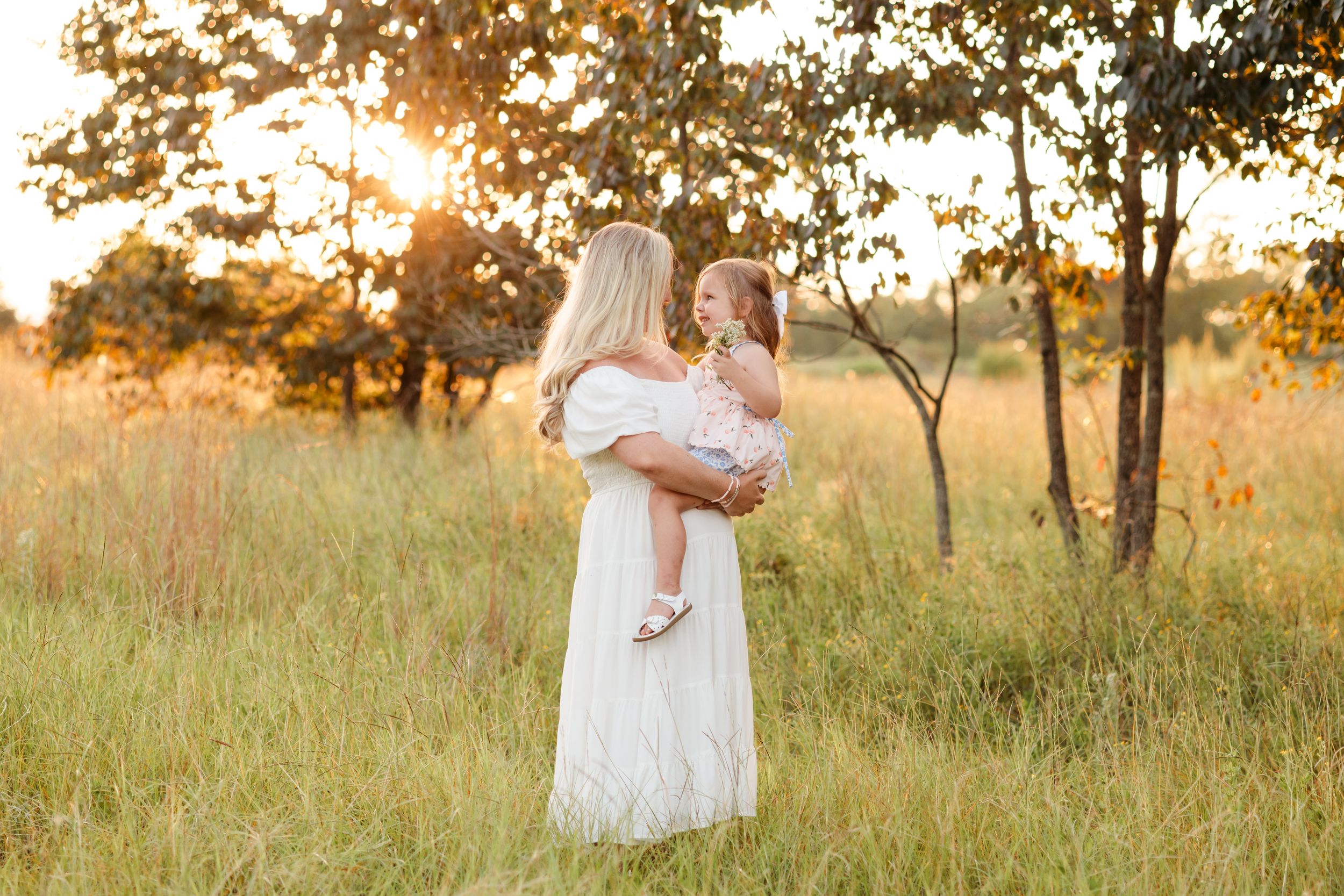 A tender moment between parent and child in a golden sunset field.