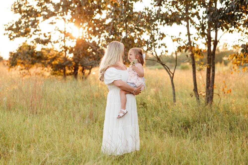 A tender moment between parent and child in a golden sunset field.