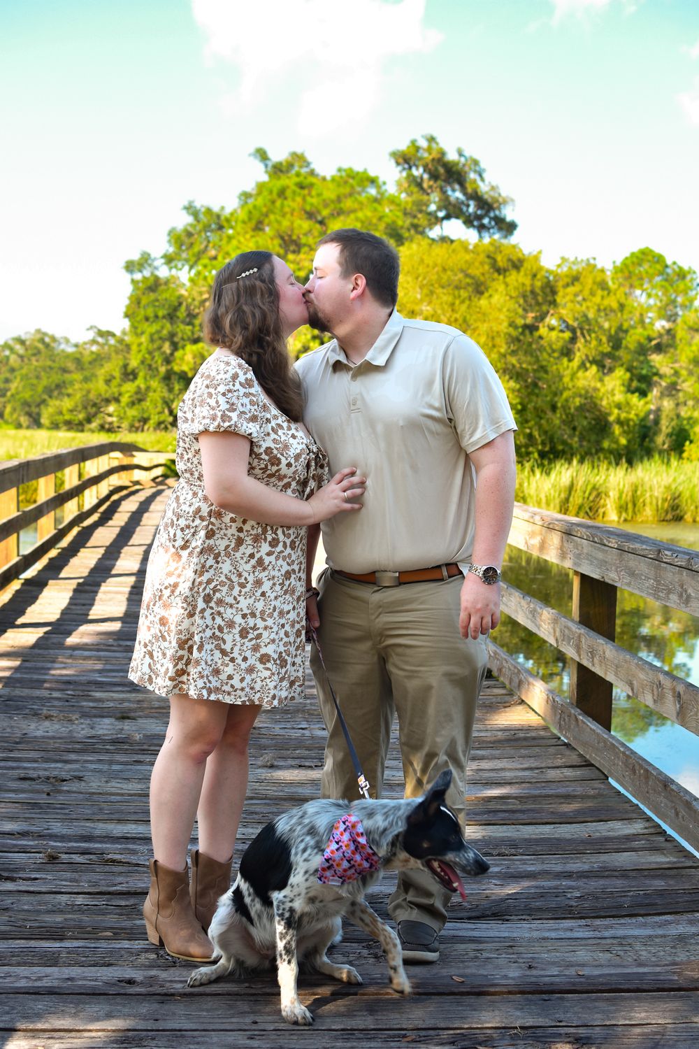 Couple sharing romantic moment on wooden boardwalk with their dog.