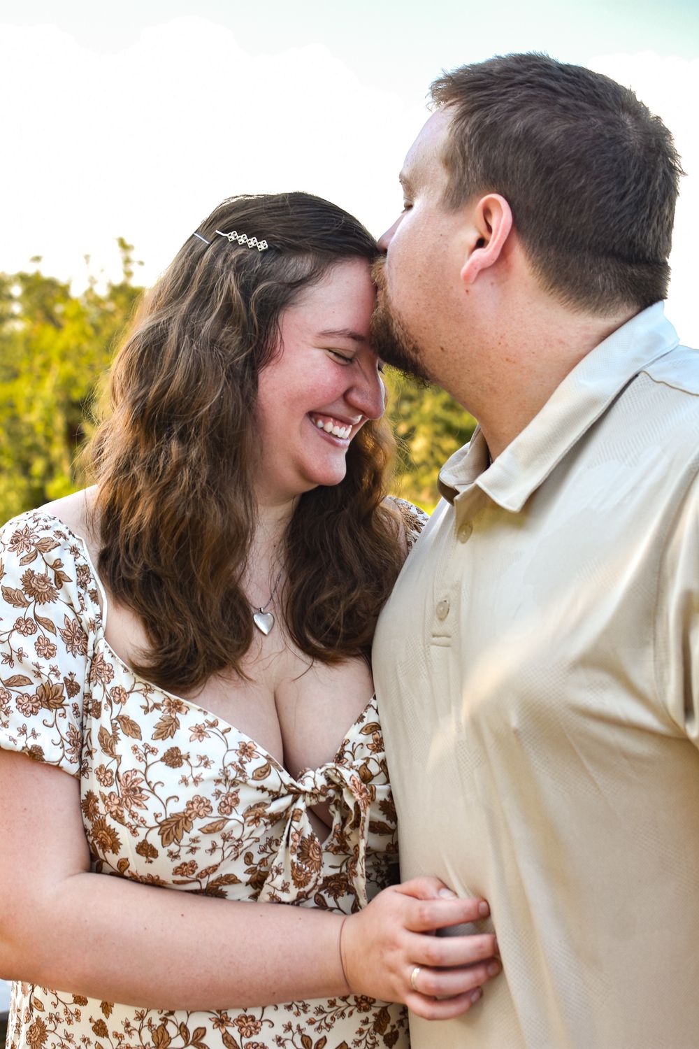 Intimate moment shared between a couple during an outdoor photo session at sunset.