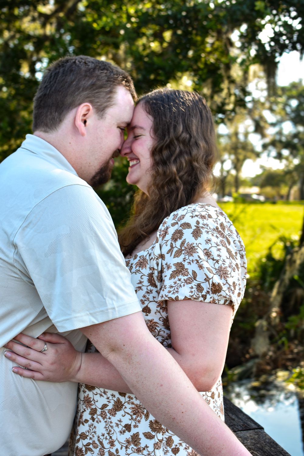 Romantic couple sharing a close moment outdoors with greenery in the background.