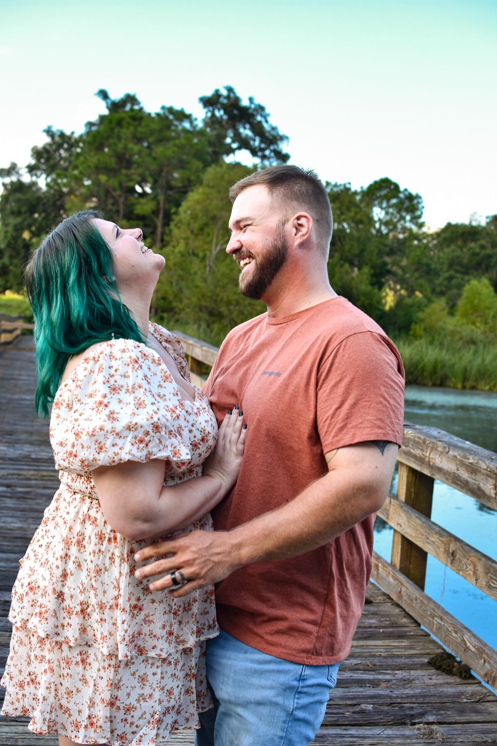 Couple sharing a joyful moment on a wooden boardwalk over marsh waters.