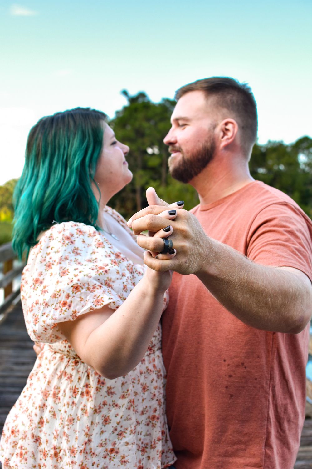 Couple dancing and laughing together on a wooden boardwalk.