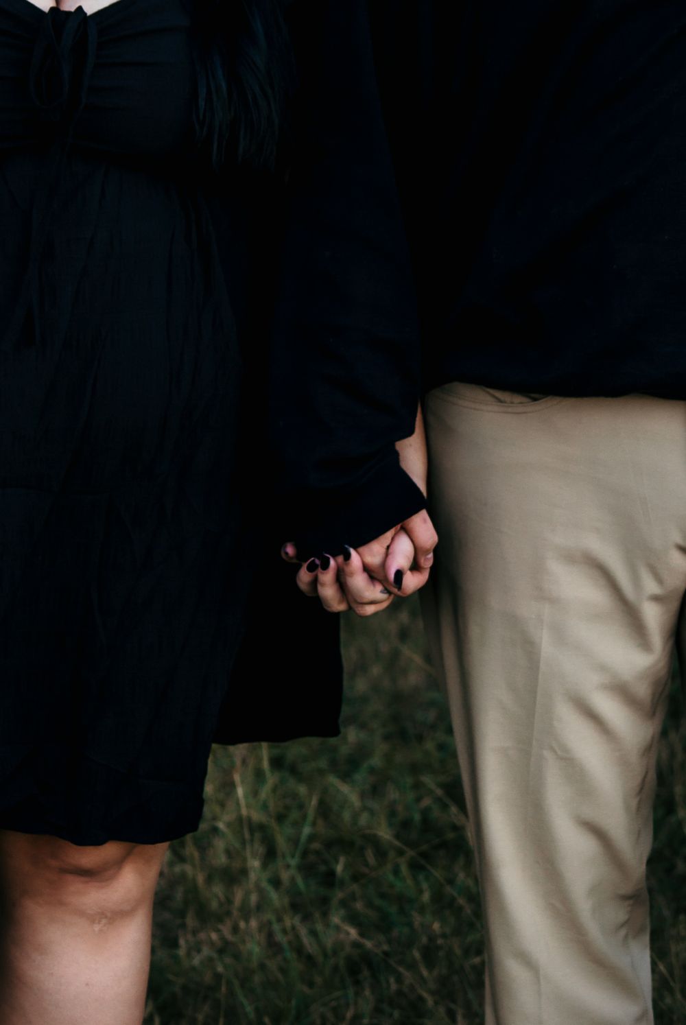 A close-up shot of two people holding hands against a dark and light clothing contrast.