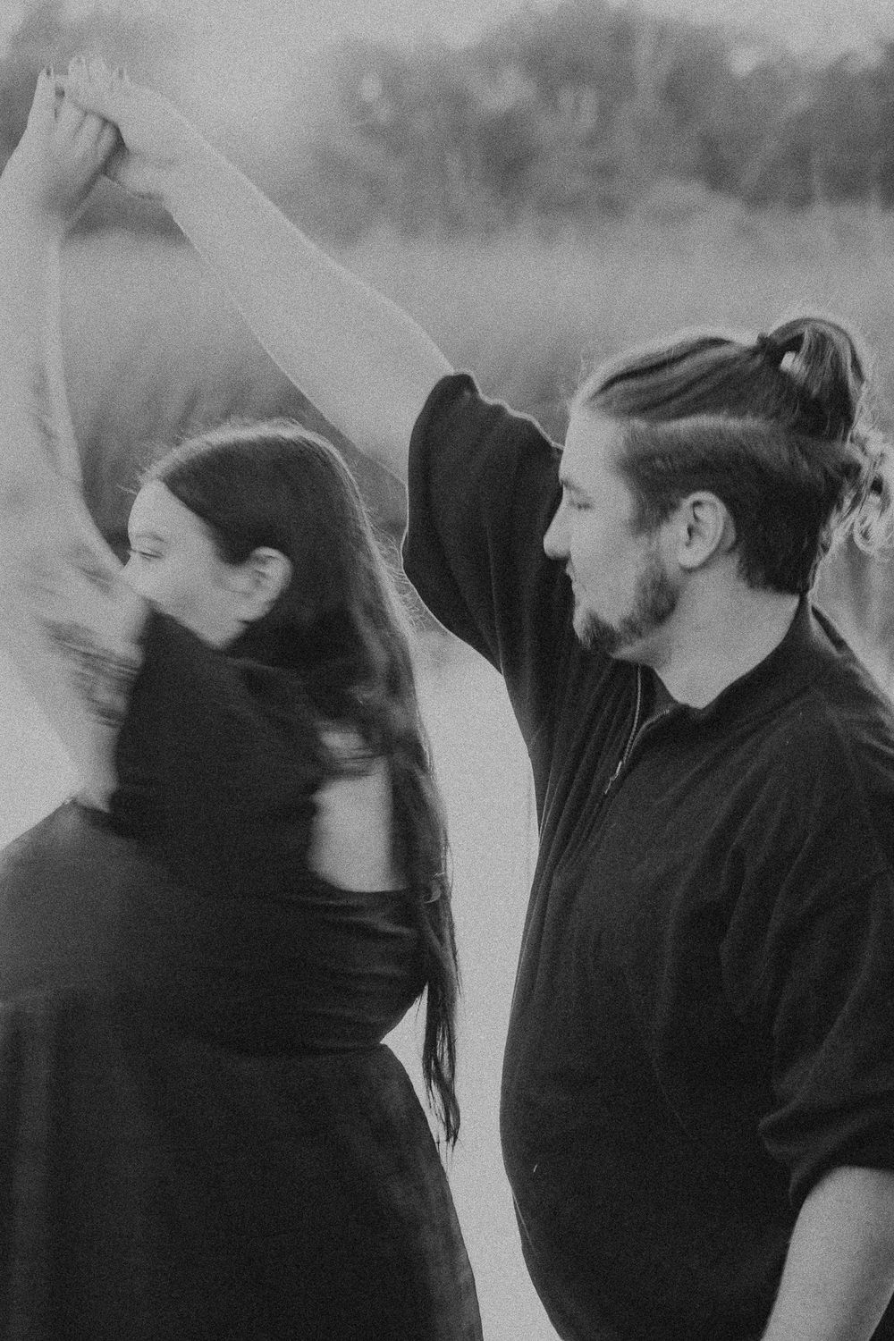 Two dancers in black attire performing an expressive dance movement in black and white.