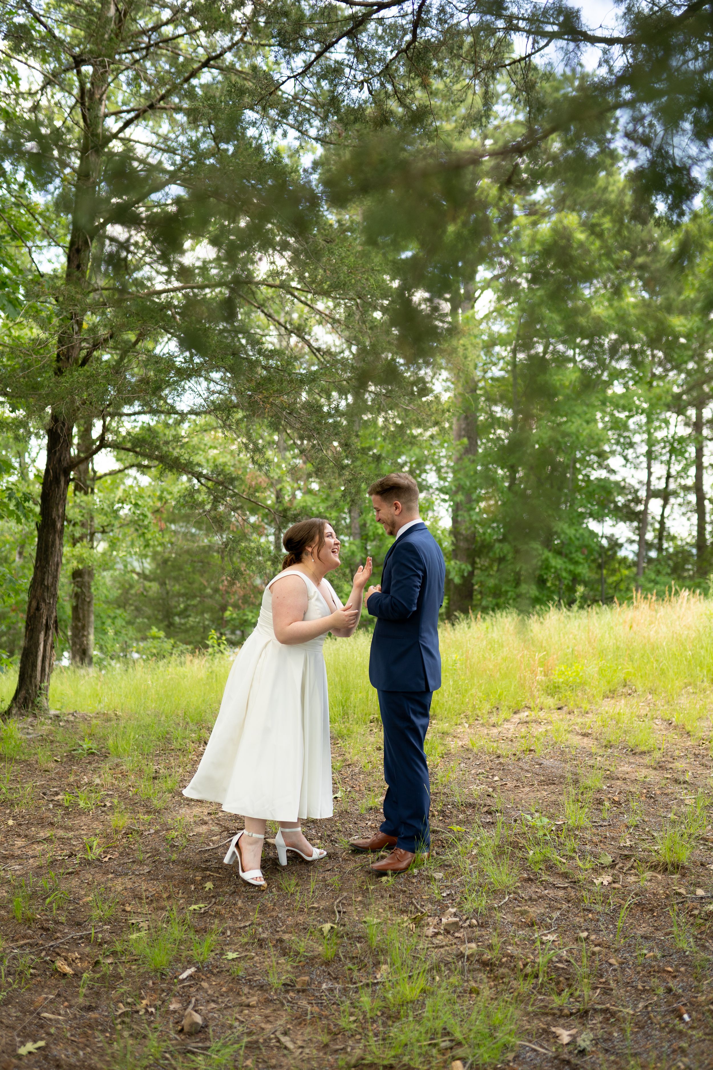 Wedding couple shares intimate moment among pine trees in outdoor setting.
