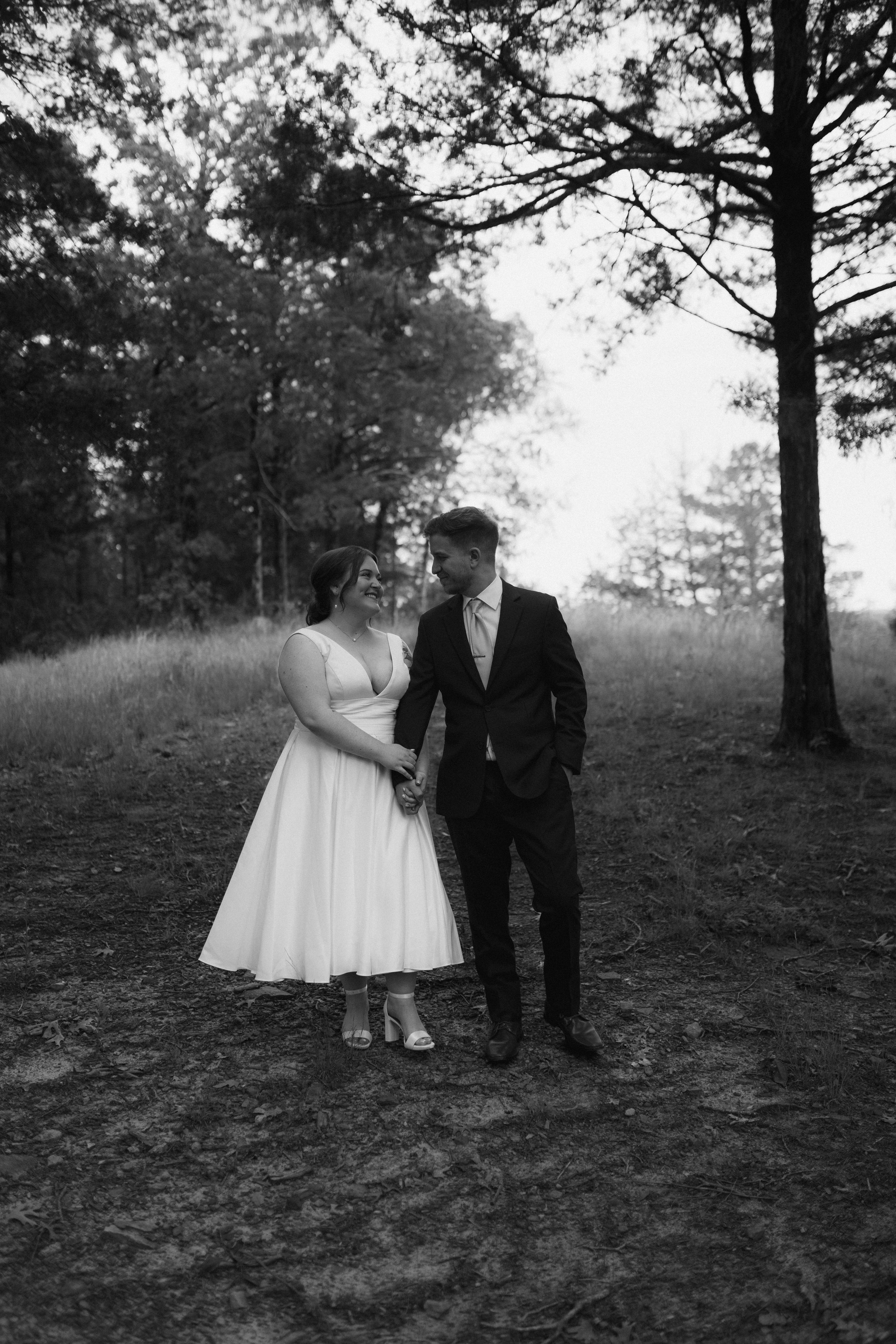 Black and white outdoor wedding portraits showing a couple in a natural wooded setting posing together.