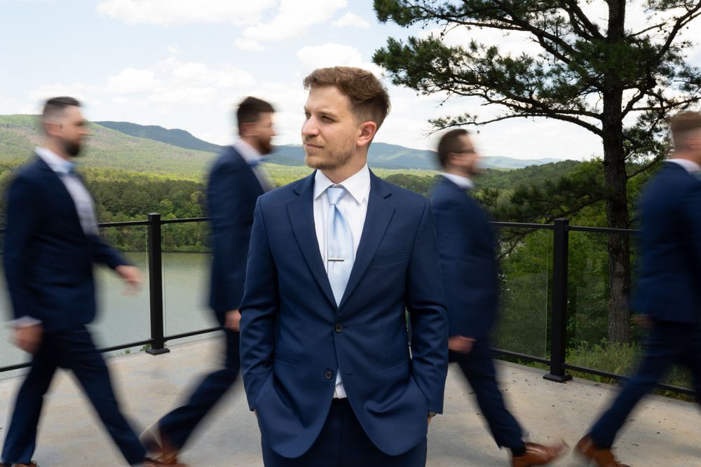 Wedding party members in navy suits walking and posing on an outdoor deck.