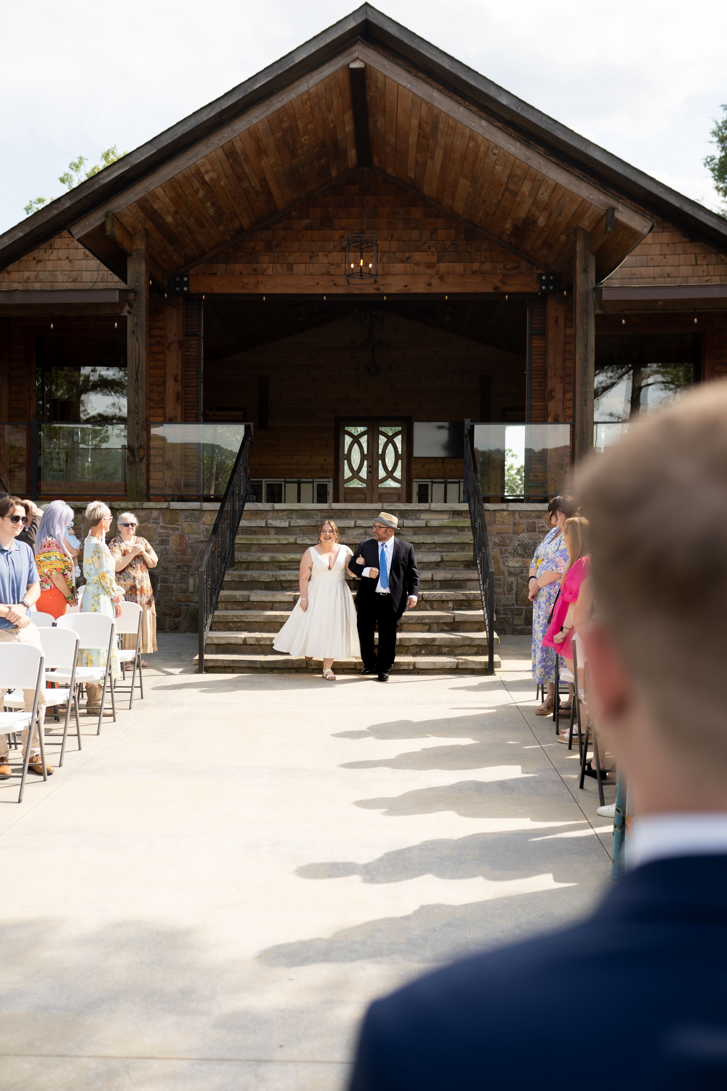 Rustic wooden wedding venue with rows of white chairs set up for an outdoor ceremony.