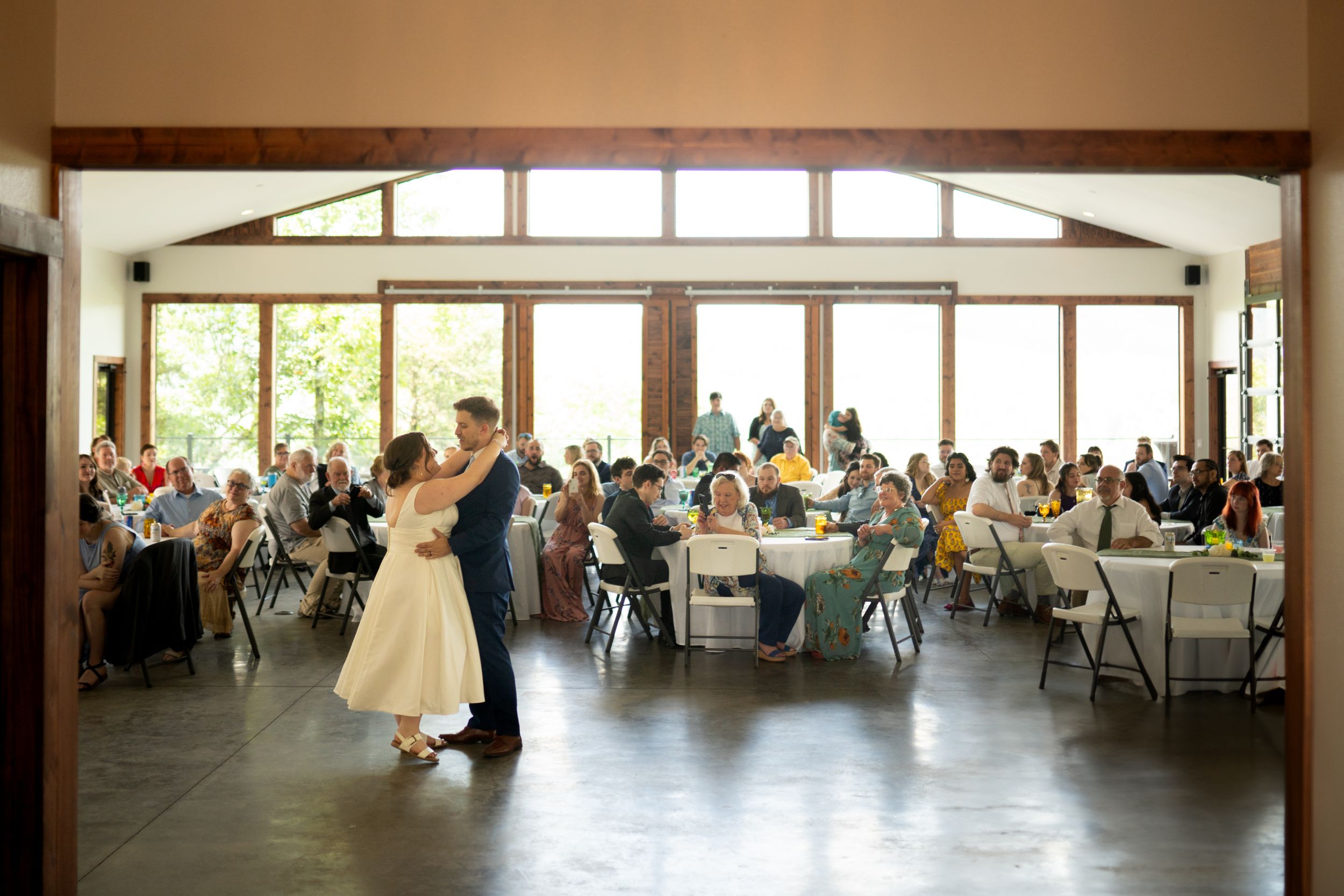 Panoramic view of a wedding reception venue with large windows and tables set for guests.