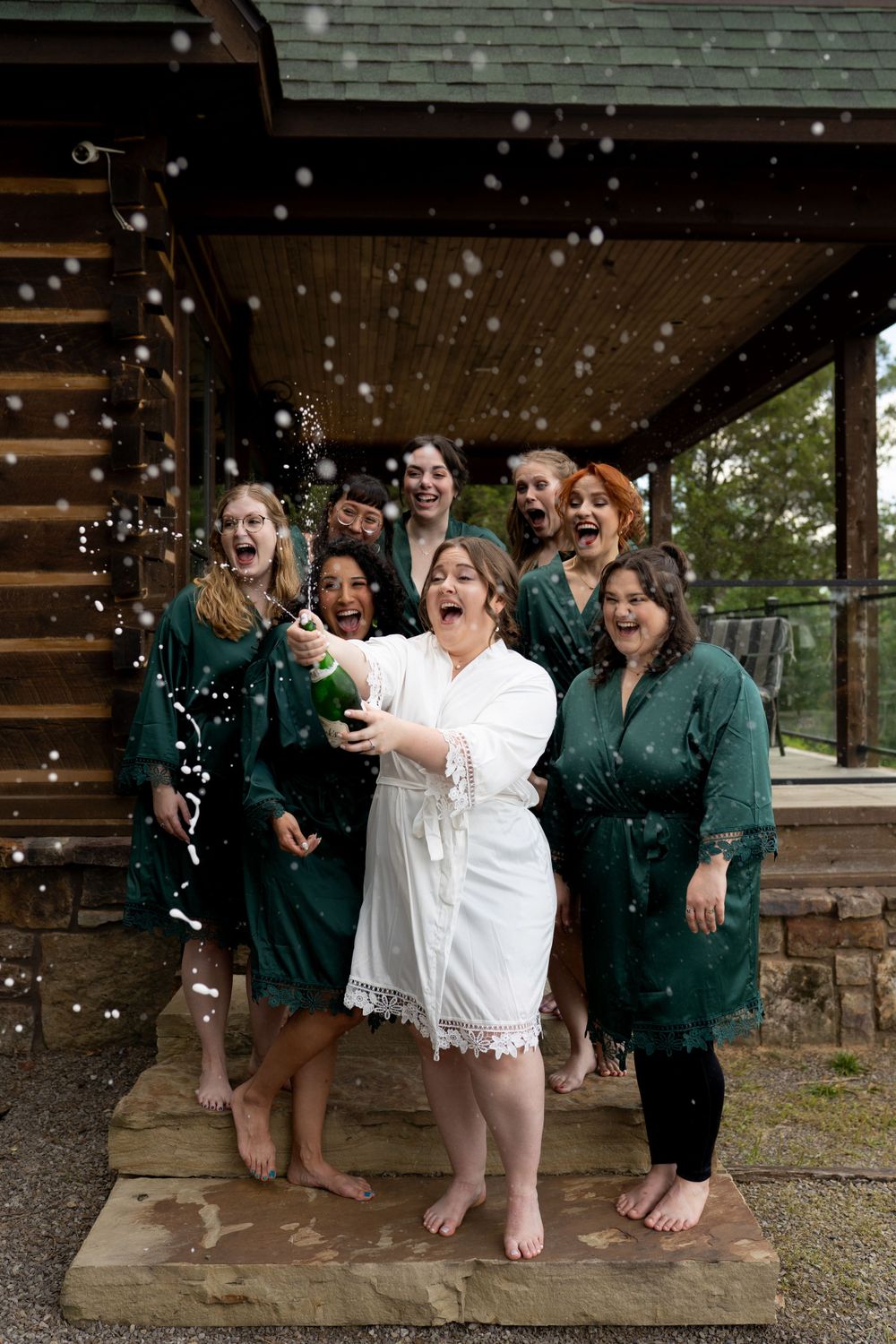 Wedding party celebrates joyfully on porch while confetti falls.