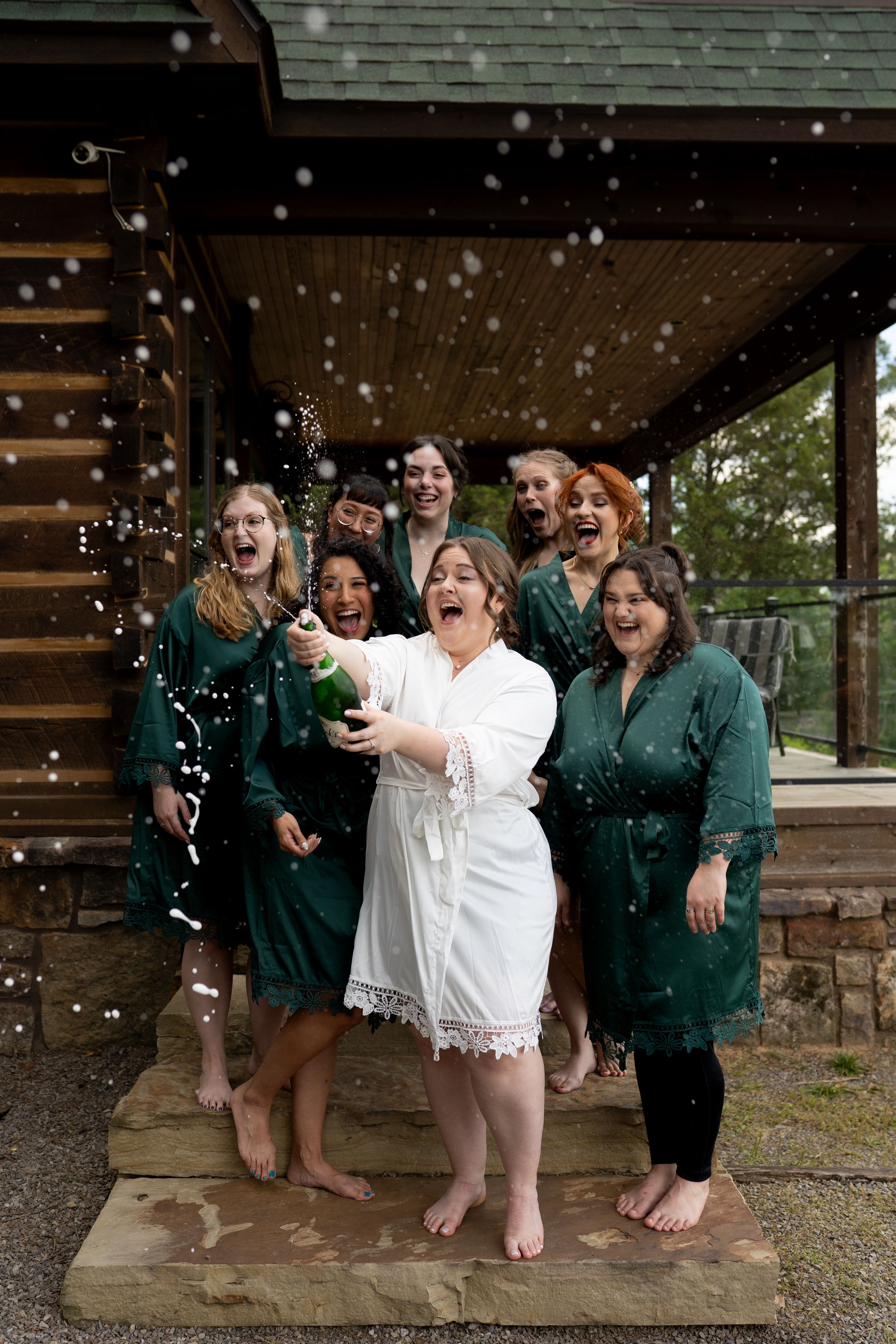 Wedding party celebrates joyfully on porch while confetti falls.