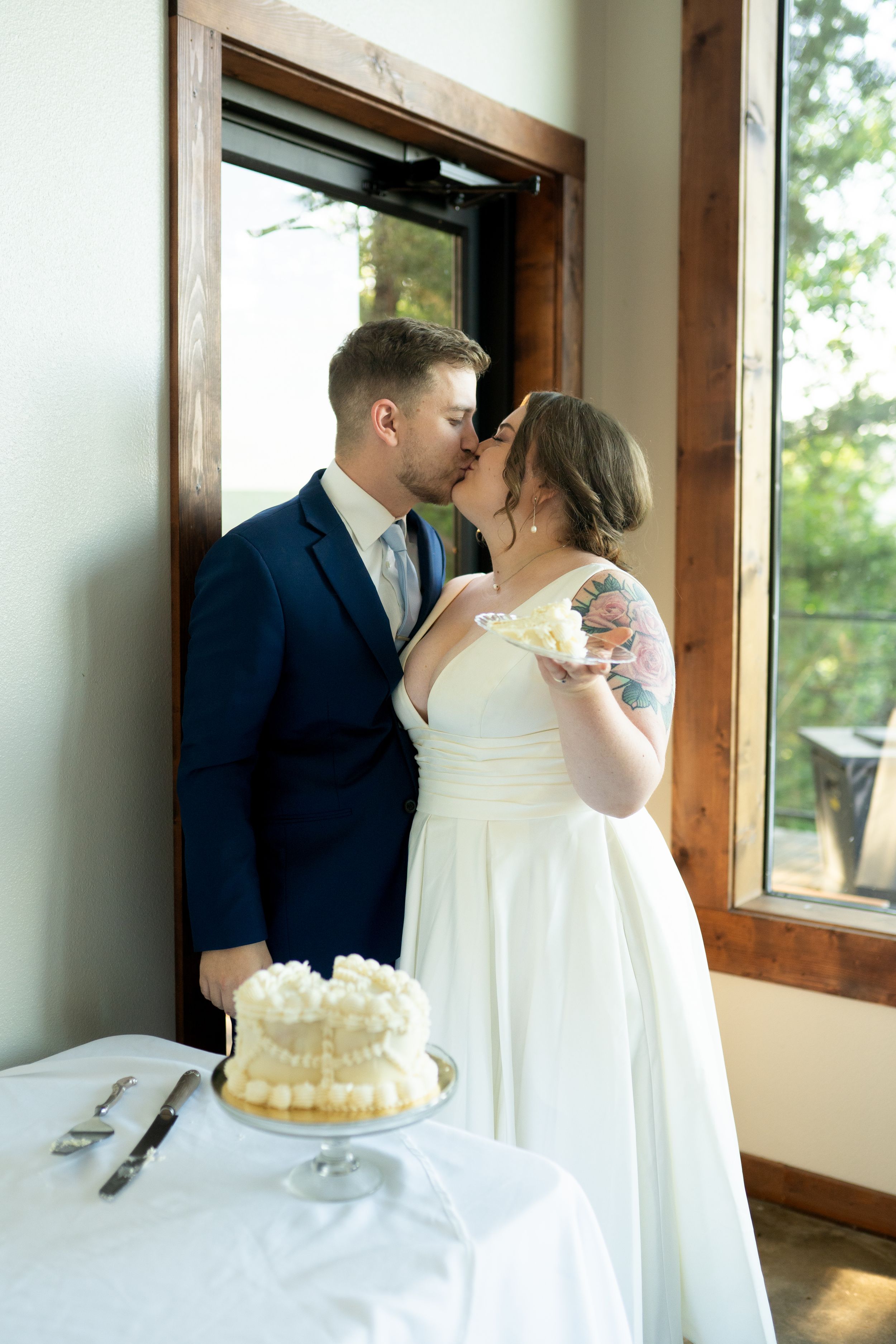 A couple cutting their white wedding cake together at a reception.