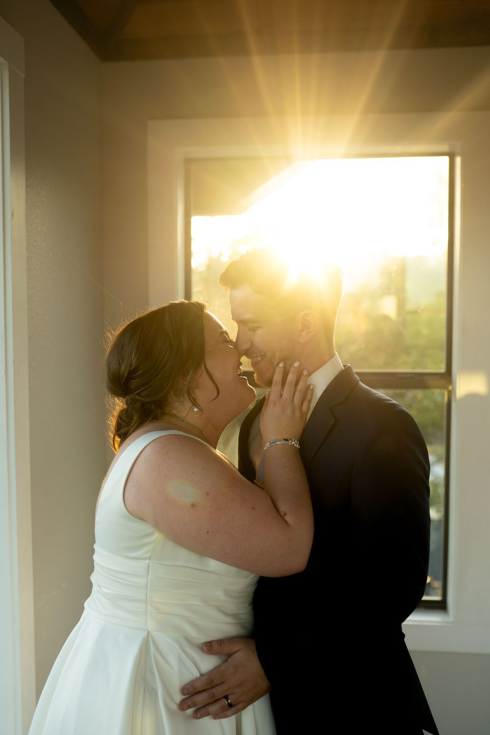 Romantic sunset silhouettes sharing a kiss by large windows.