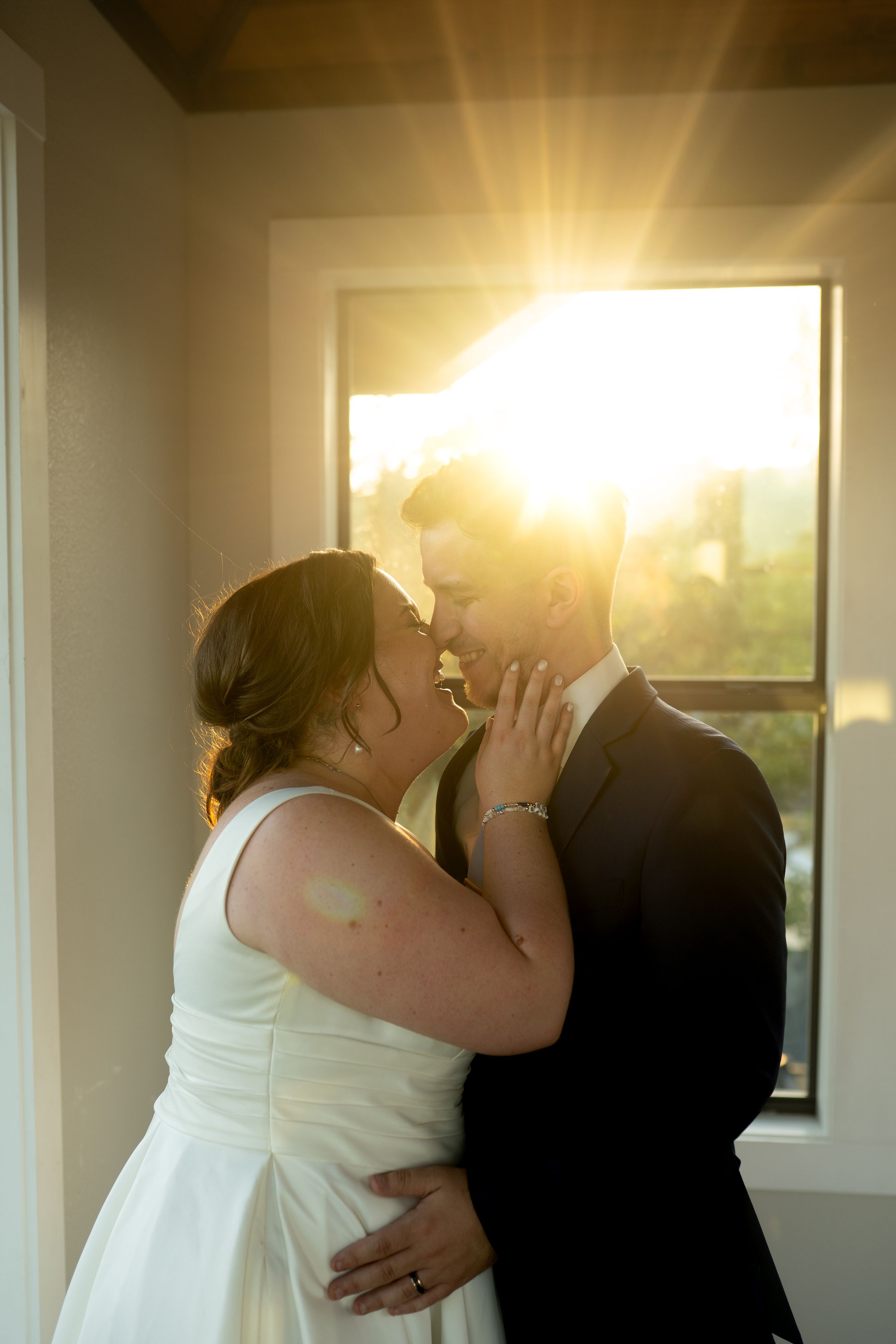 Romantic sunset silhouettes sharing a kiss by large windows.