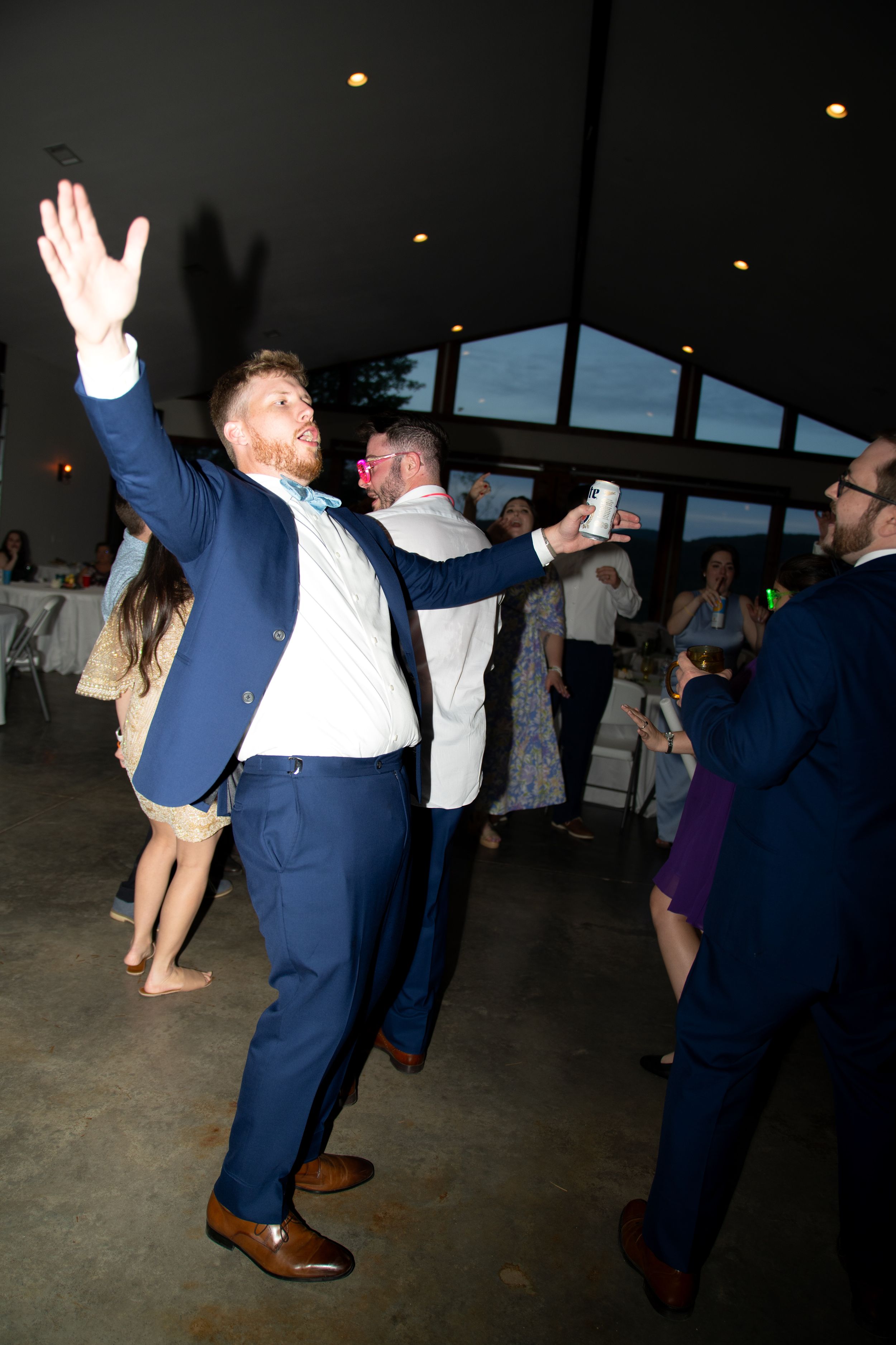 People dancing and celebrating at a wedding reception in navy blue suits.