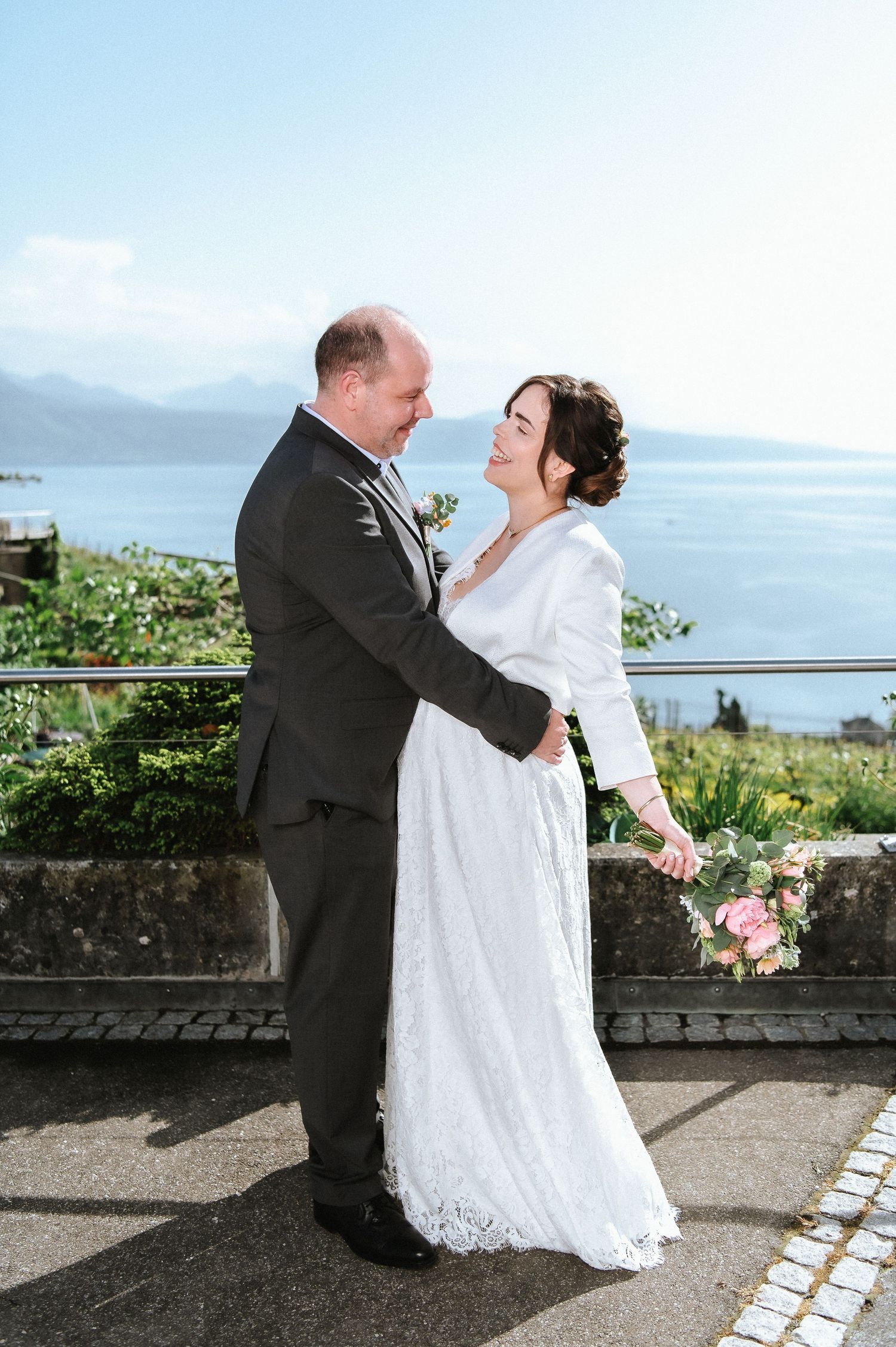 Newlyweds dance and embrace on an oceanside terrace during their wedding celebration.
