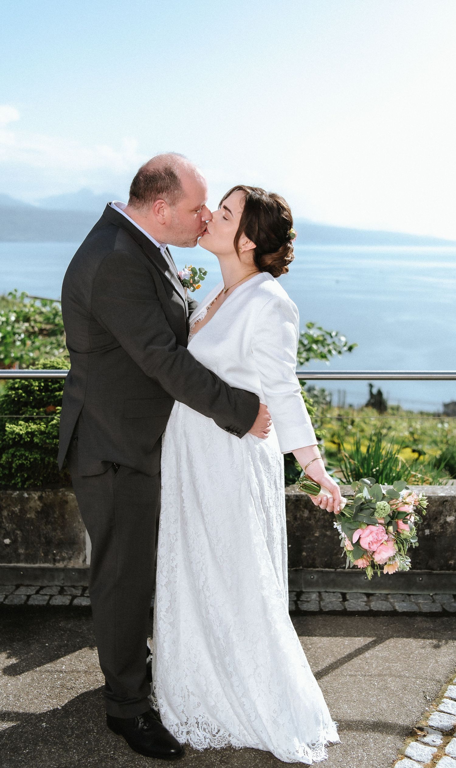 Couple shares their first dance as newlyweds on a scenic terrace by the ocean.