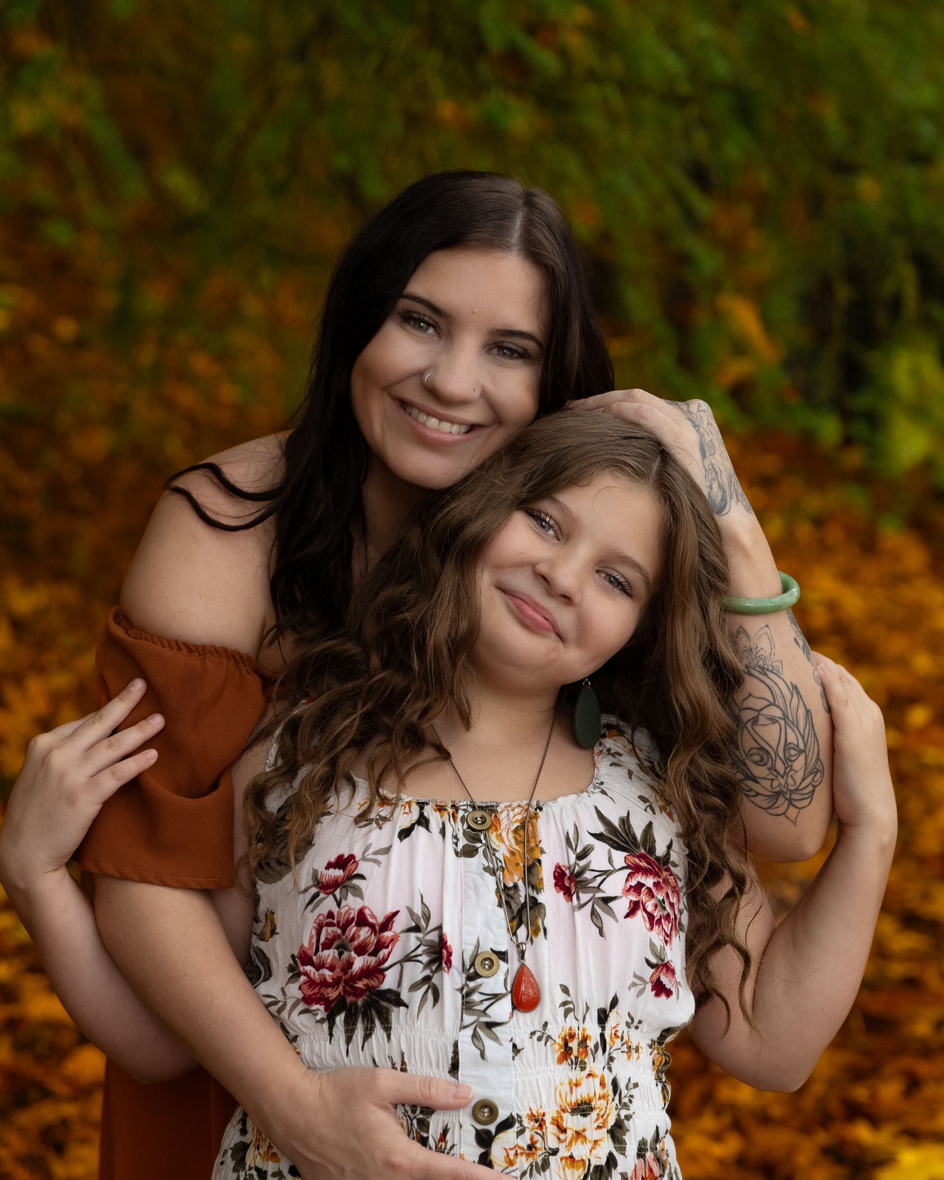 Jessica hugs her daughteri, surrounded by orange fall foliage, during a fall family session in Tacoma, Washington.