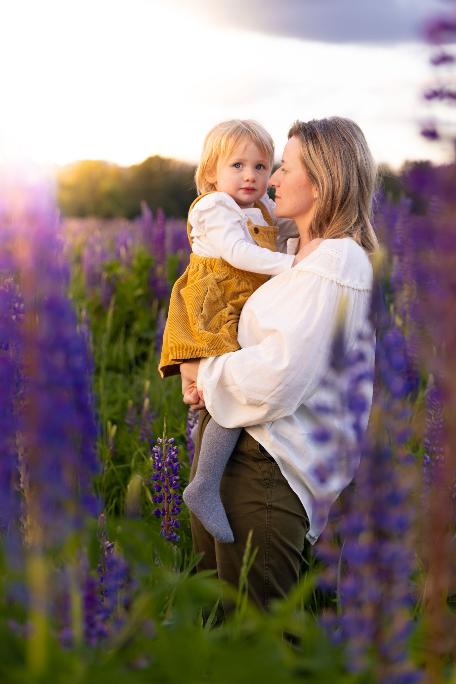 A mother looks lovingly at her daughter during golden hour in a field of purple flowers in Washington.