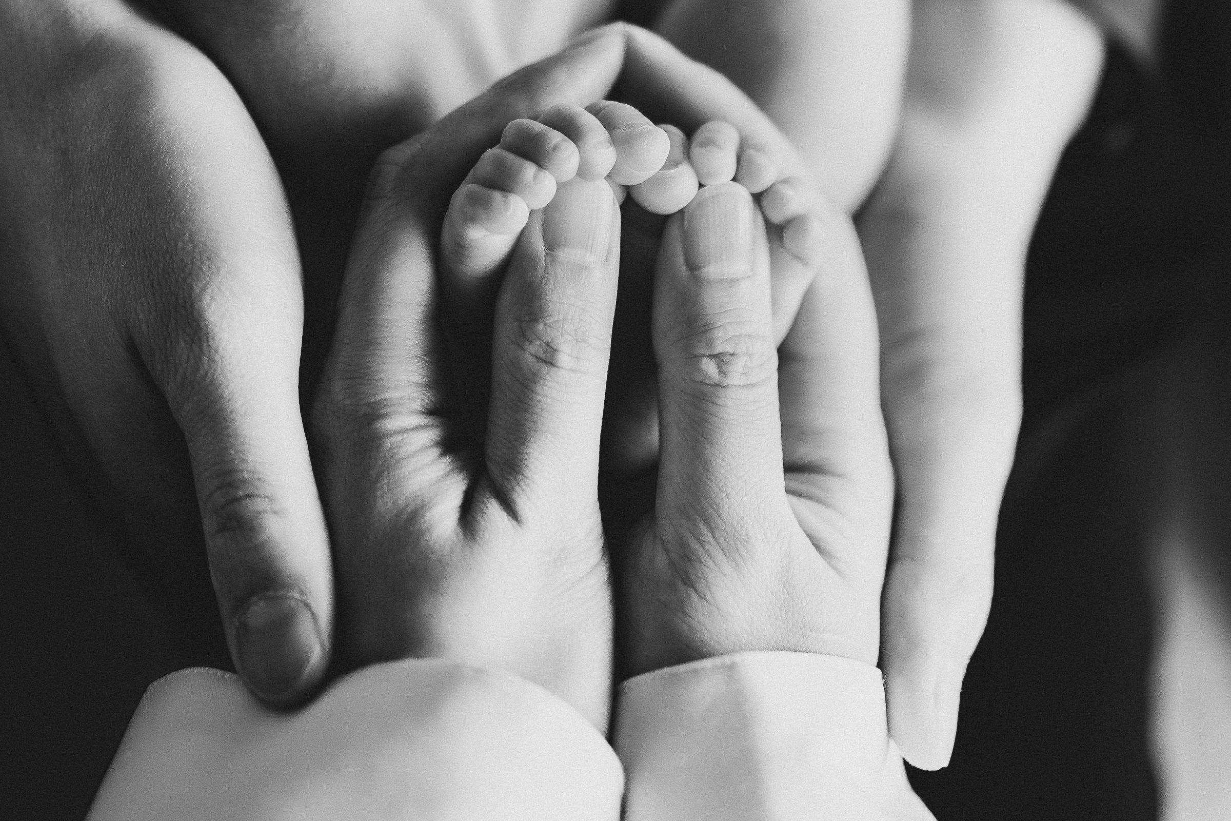 New mom and dad hold their newborn baby girl's tiny feet during a lifestyle newborn session in Bonney Lake, Washington.
