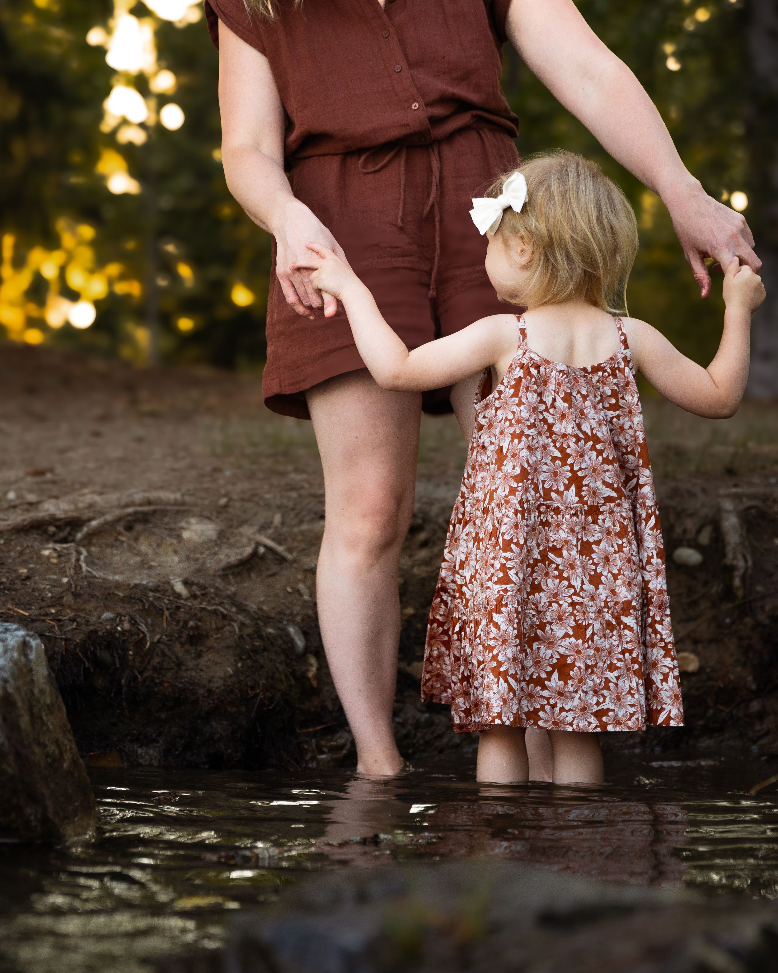 Mom and daughter hold hands standing in Lake Tapps during a family photography session with Jess Paige Photography.