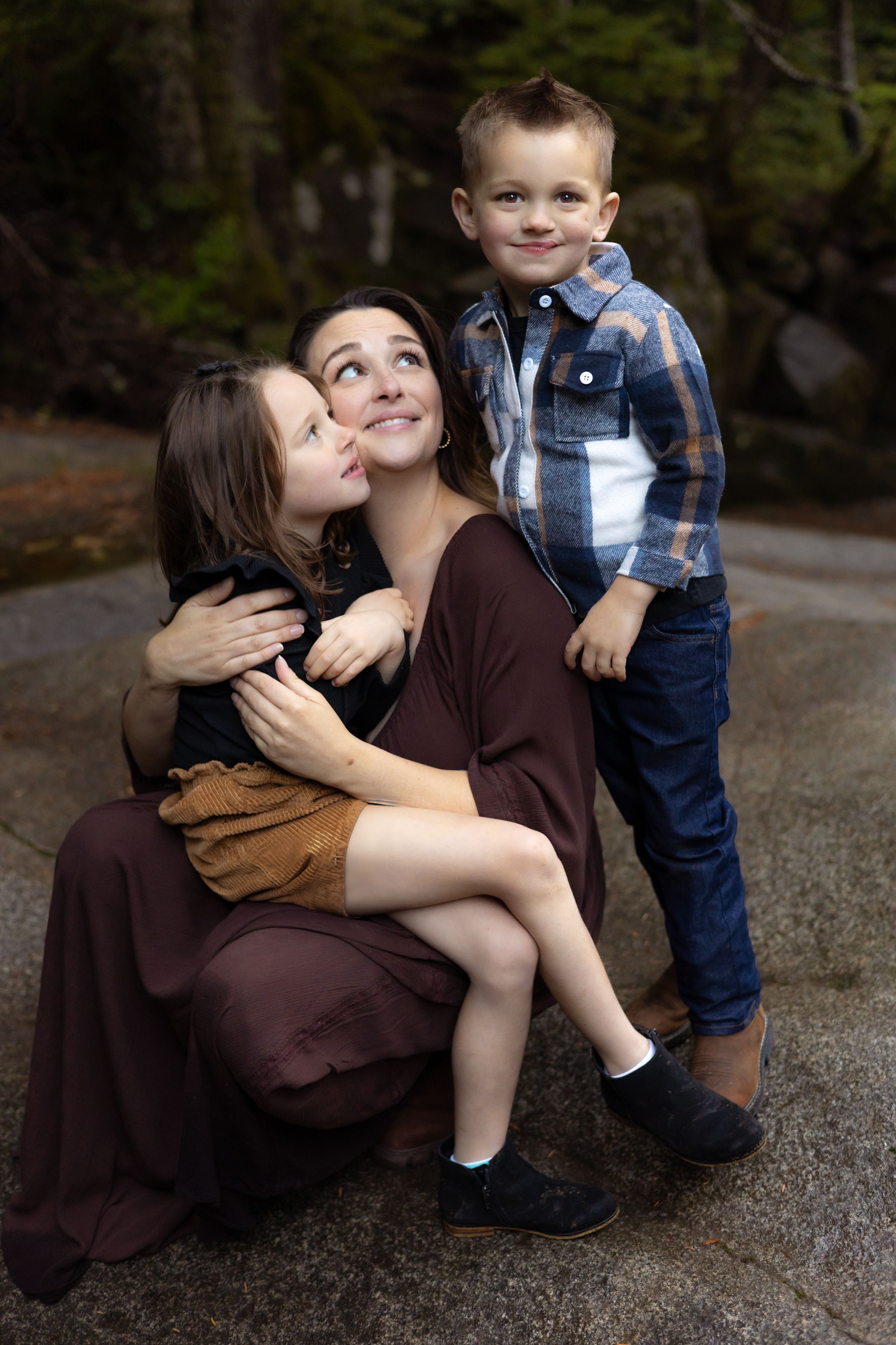 A mom looks at her son and holds her daughter during an adventure family session near Seattle.