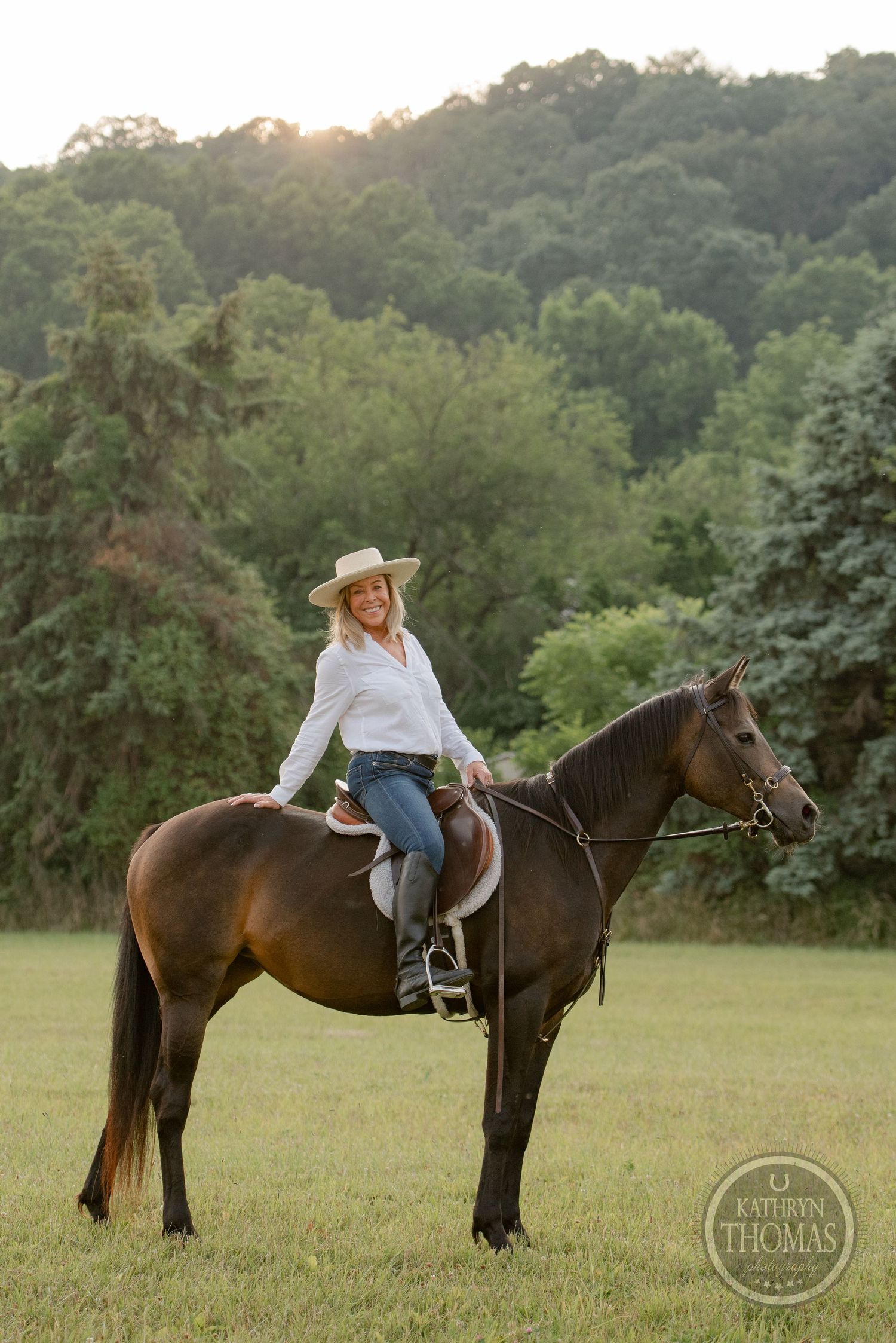 A stunning dark horse being ridden in a scenic field during golden hour.