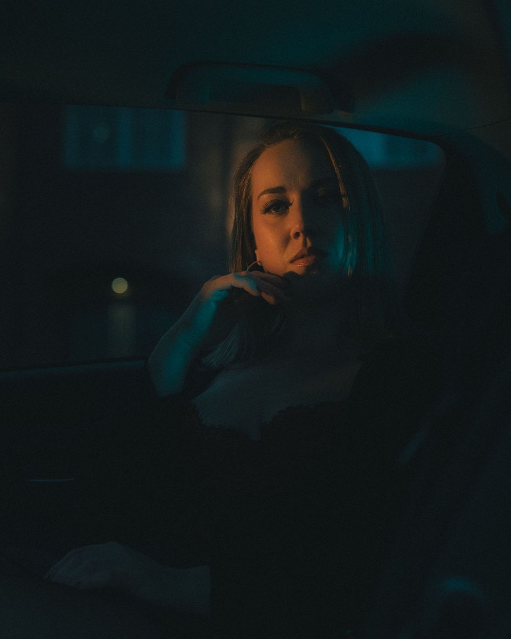 A moody nighttime photo inside a car with dramatic teal lighting creating an atmospheric cinematic ambiance.