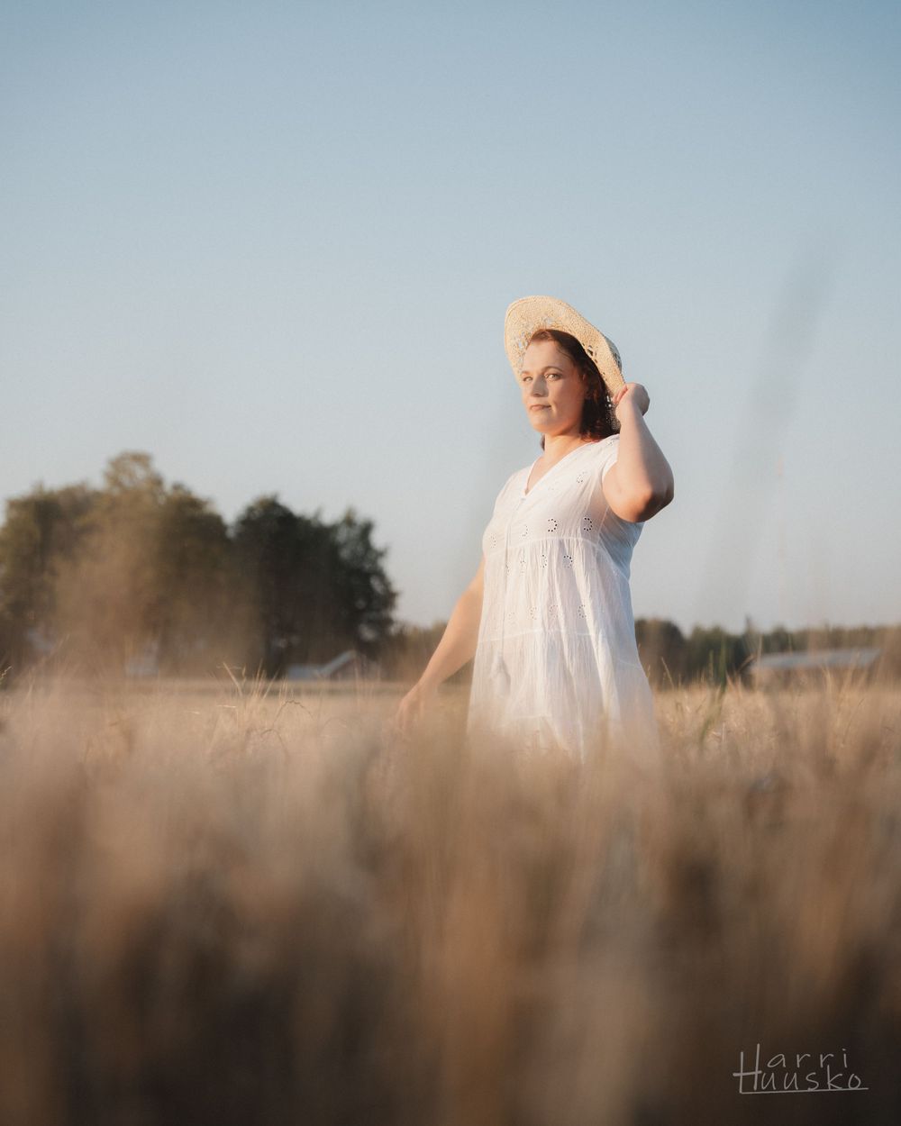 A dreamy summer portrait in a wheat field with a white dress and sun hat.