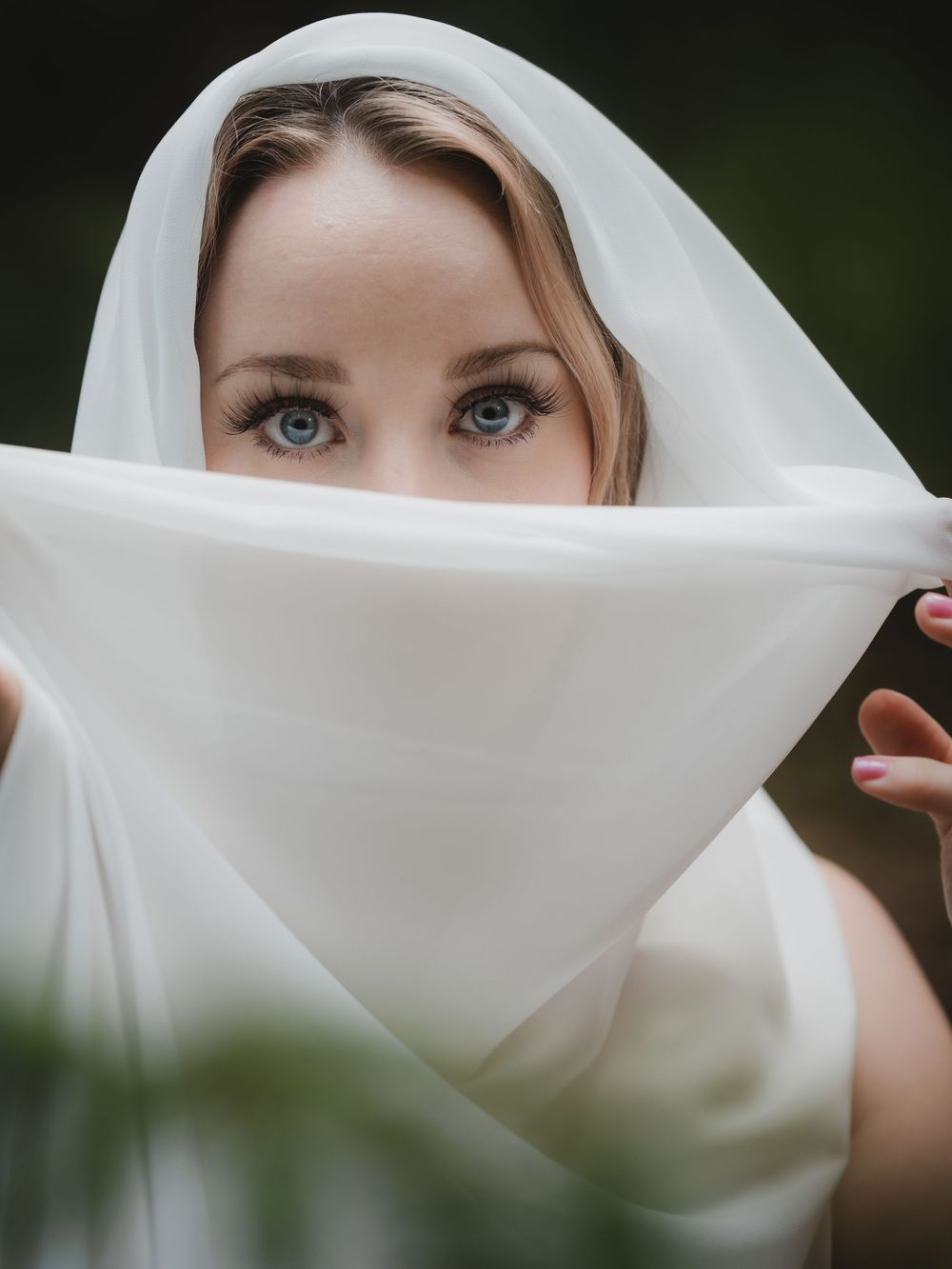A flowing white veil creates an elegant sequence of flowing motion in outdoor bridal portraits against a dark background.