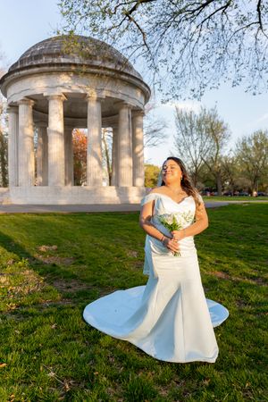 Beautiful bride posing in a white wedding gown in front of a classical domed monument at sunset. wedding photographer videographer